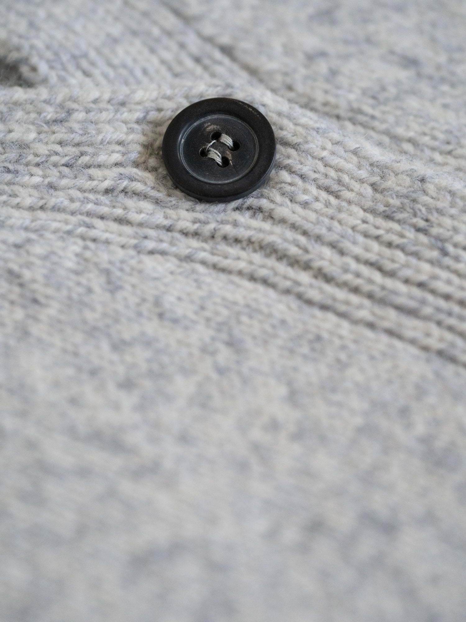 Detail des Knopfs der FUXBAU Merino Strickweste – feine Strickstruktur in Graumeliert, hochwertig verarbeitet