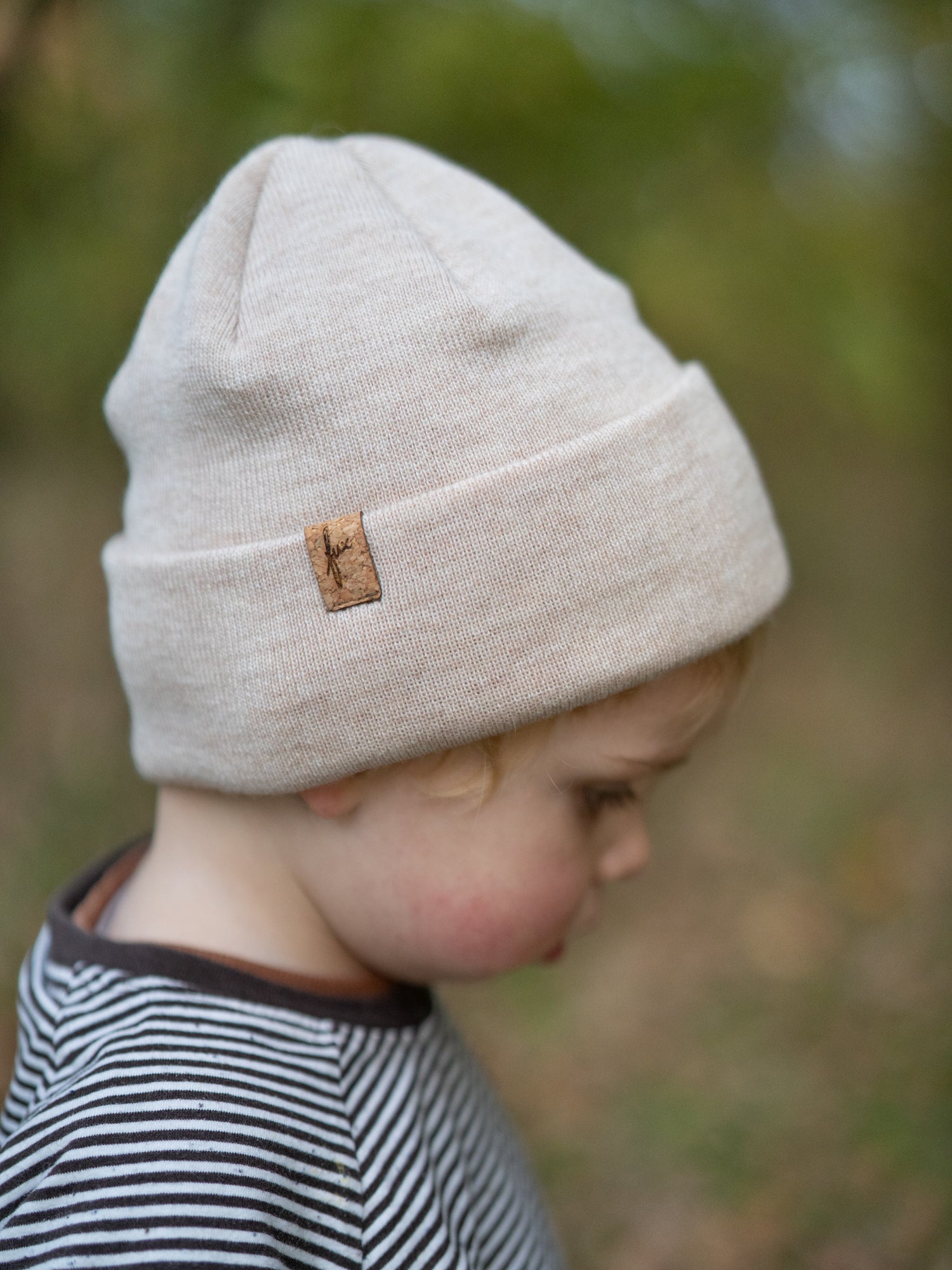 Kind trägt FUXBAU Kinder Beanie aus Merinowolle in Naturweiß – nachhaltige Mütze mit Korklabel, fair gefertigt in Deutschland