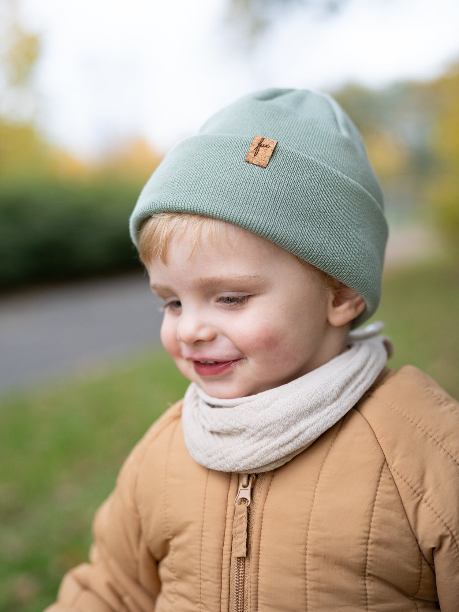 Kind mit FUXBAU Merino Beanie in Seegrün – nachhaltige Kinder Mütze mit Korklogo, fair produziert in Deutschland