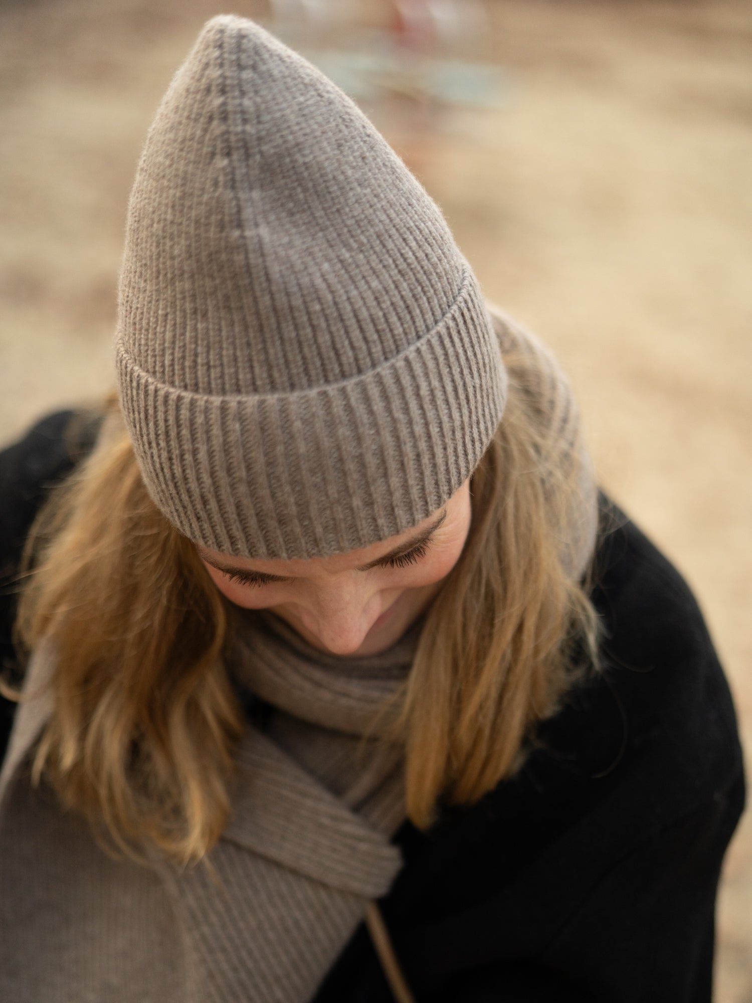 Frau trägt eine braunmelierte Merino Mütze von FUXBAU – weiche italienische Strickqualität, warm & nachhaltig gefertigt.