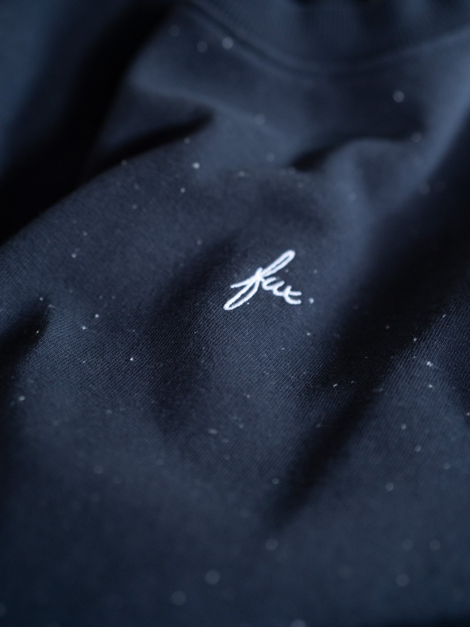 Detailaufnahme des navyblauen FUXBAU Neps Pullovers aus Bio-Baumwolle – feine Struktur mit weißen Neps und gesticktem FUX-Logo