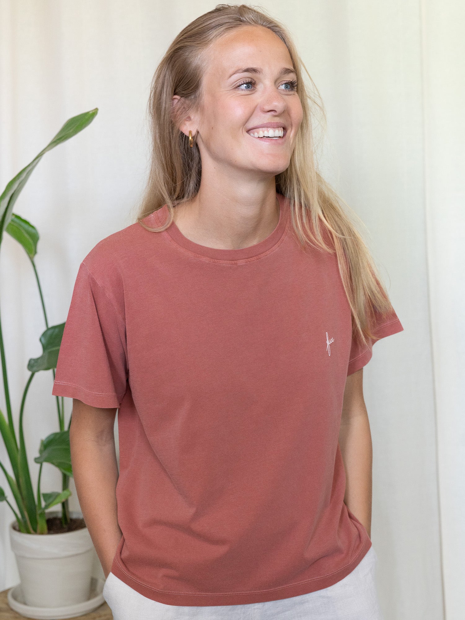 Greta ist 1,72m trägt Größe M im rotem T-Shirt von FUXBAU, dass fair und nachhaltig in Portugal hergestellt wird.