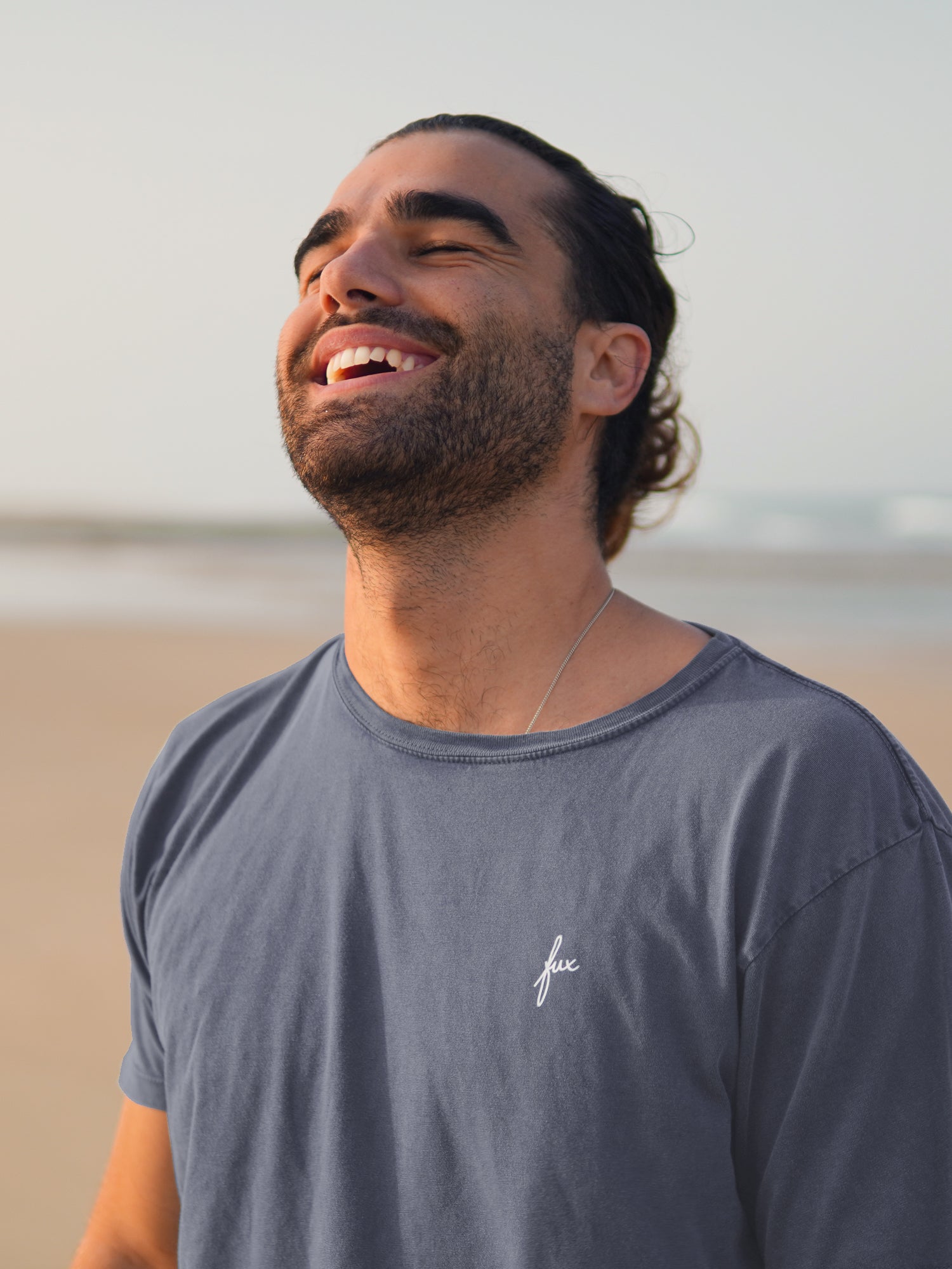 Guillermo trägt das nachhaltige Männer fux T-Shirt in blaugrau aus 100% Biobaumwolle am Strand