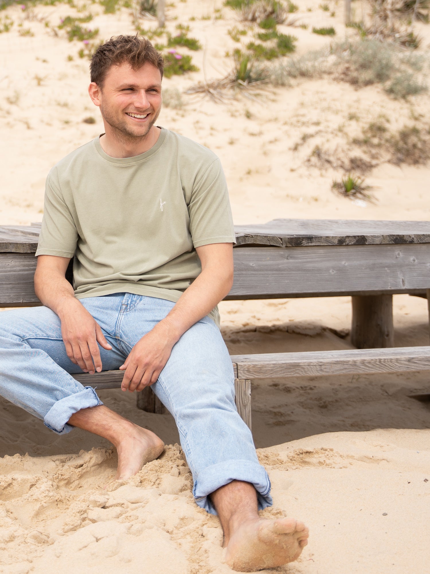 Nachhaltiges Männer T-Shirt in seegrün getragen von einem jungen Mann am Strand