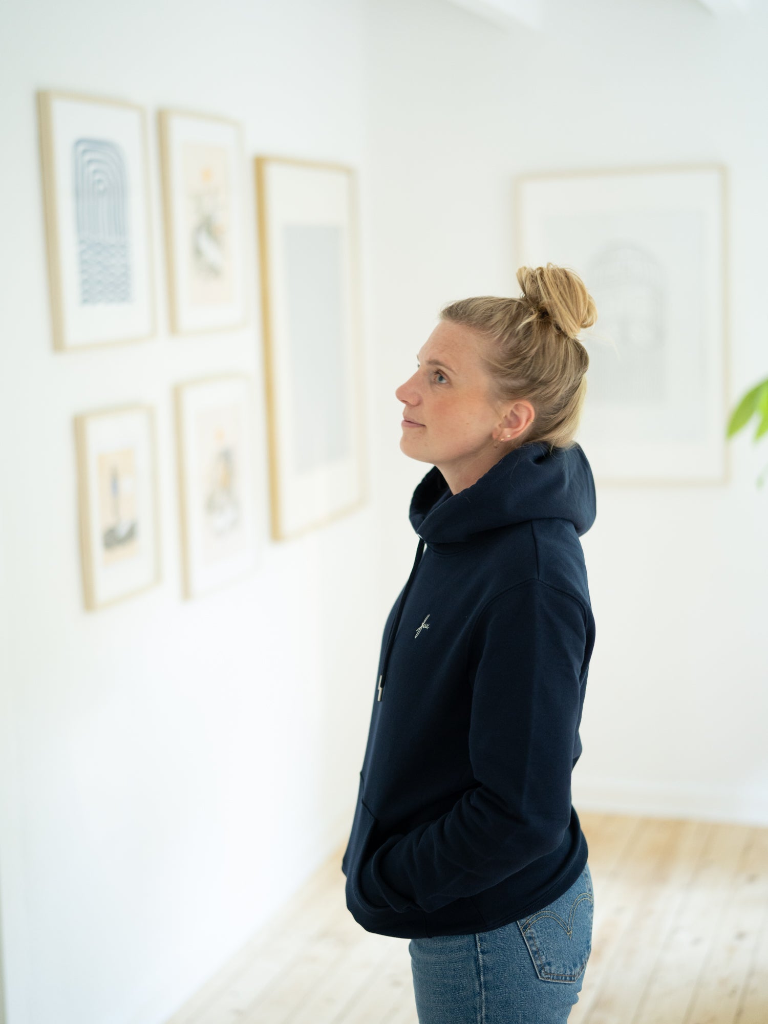 Eine junge, blonde Frau trägt einen fair und nachhaltig produzierten Unisex Hoodie von FUXBAU in navy.