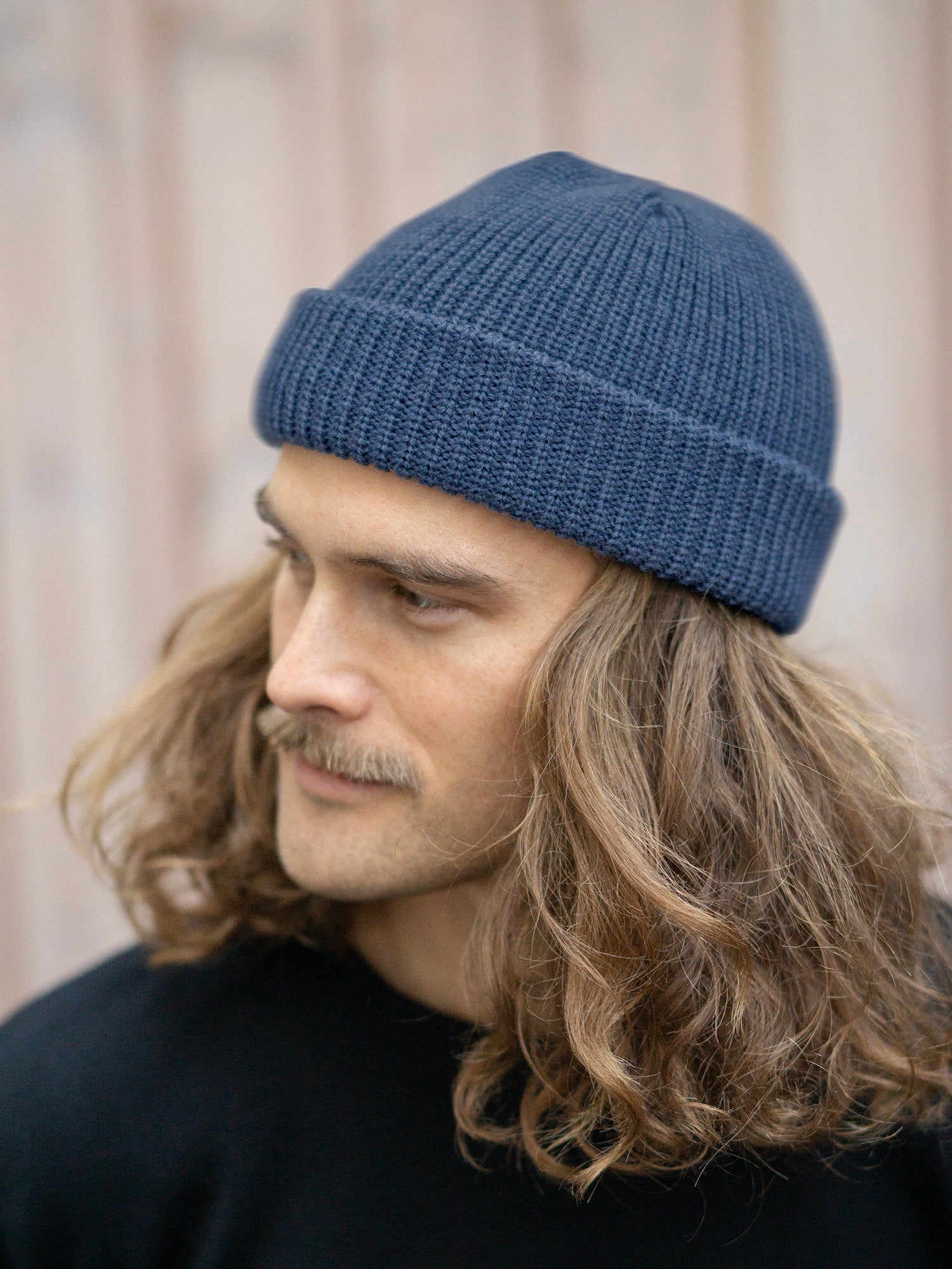 Unser Freund Kelsey trägt die Kurze Merino Strickmütze in nachtblau von FUXBAU aus 100% GOTS zertifizierter Merinowolle made in Germany