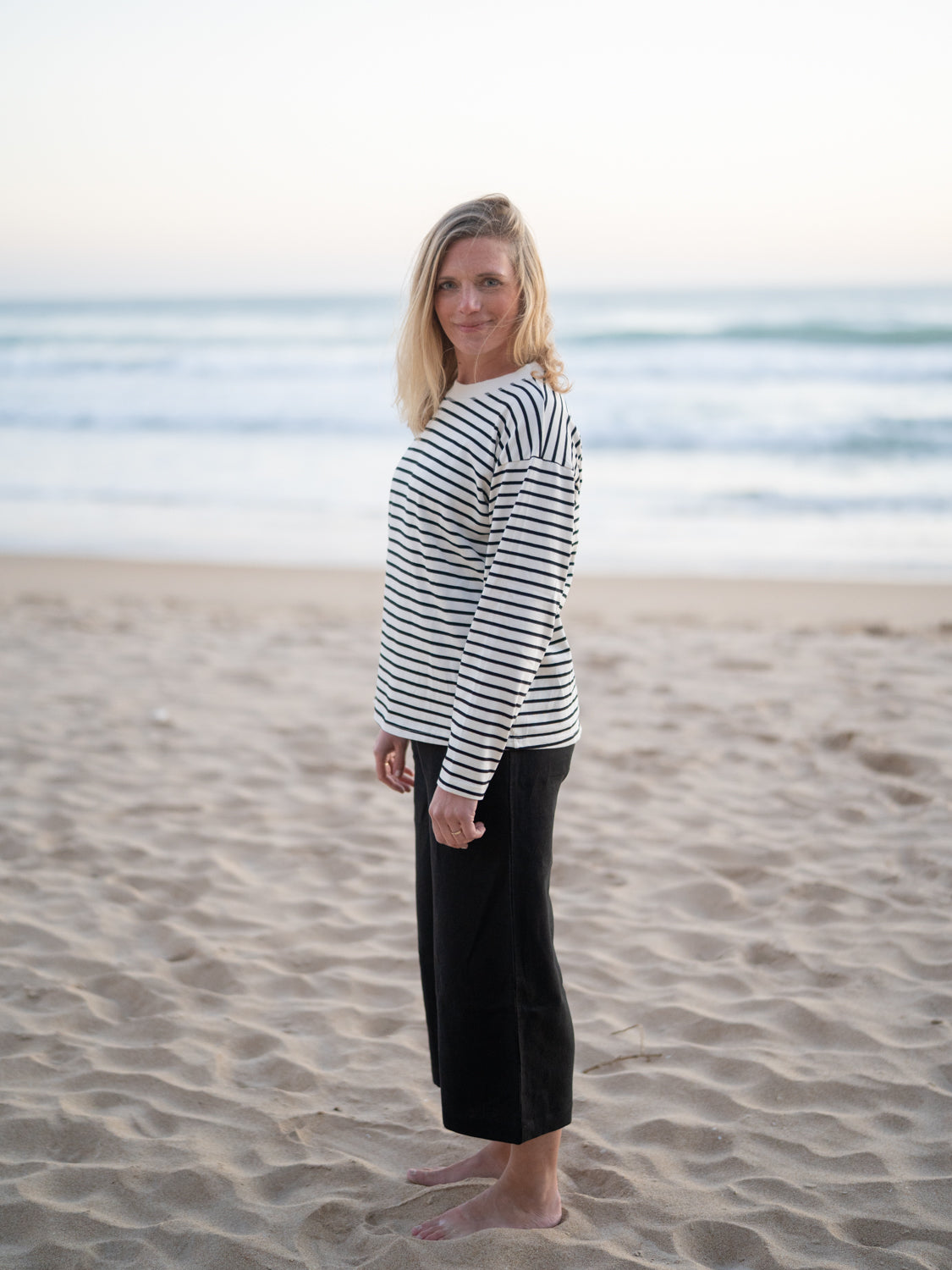 Nachhaltige FUXBAU Fair Fashion Frauen Leinehose in schwarz aus 100% Leinen getragen am Strand in Spanien.