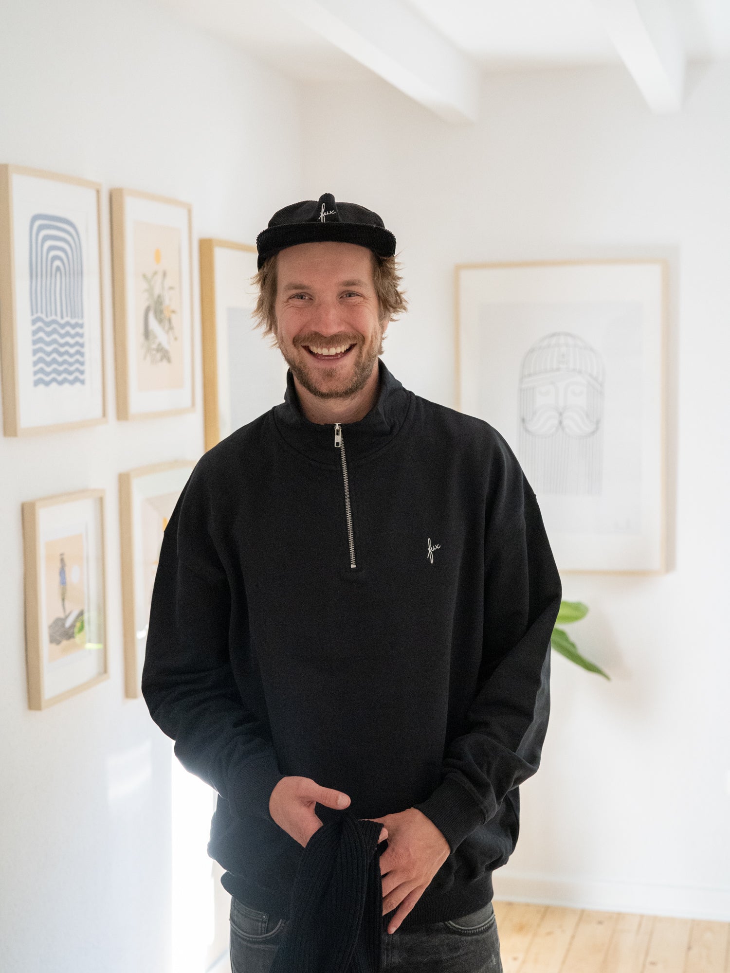 Kenny trägt unseren FUXBAU Fair Fashion Half Zip Sweater in schwarz aus Biobaumwolle