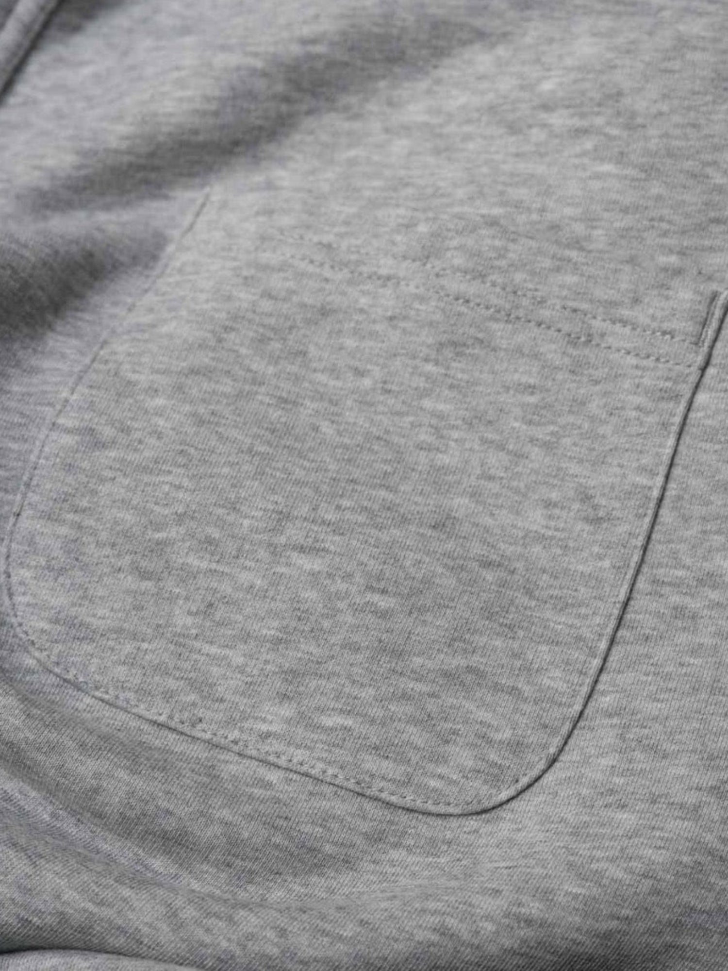 Detailansicht einer nachhaltigen fair fashion Jogginghose von FUXBAU mit Gesäßtasche auf grau meliertem Stoff aus Biobaumwolle.