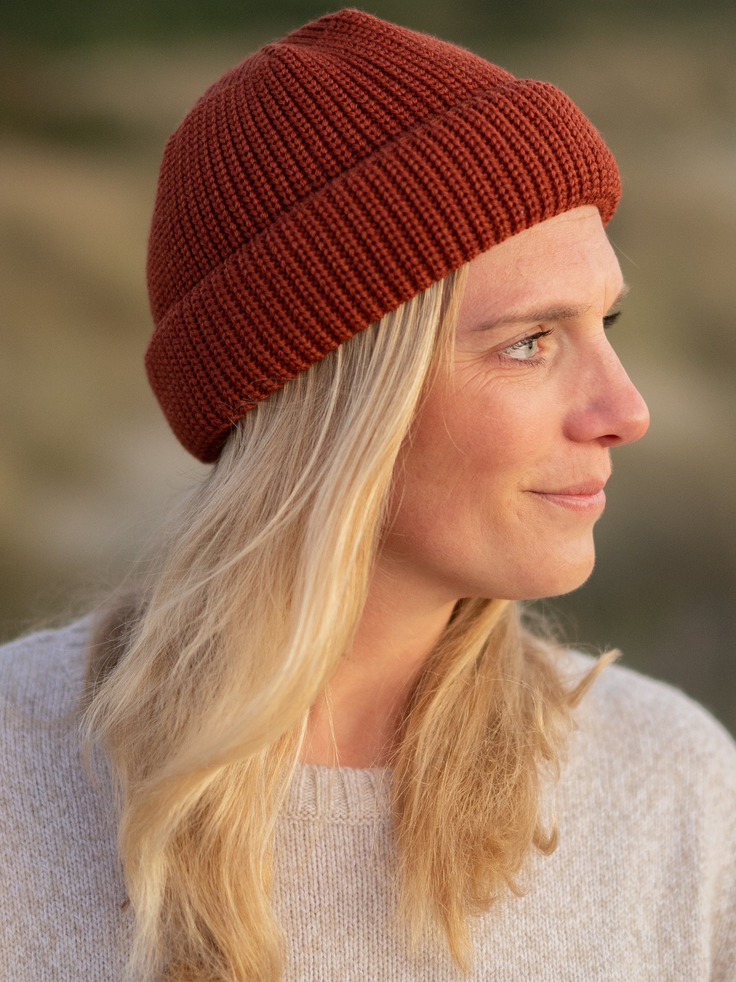 Nachhalte fair fashion kurze fischermütze von fuxbau aus gots zetifizierter Merini Schurwolle. Gestrick in Deutschland in herbstorange und getragen von einer jungen blonden Frau.