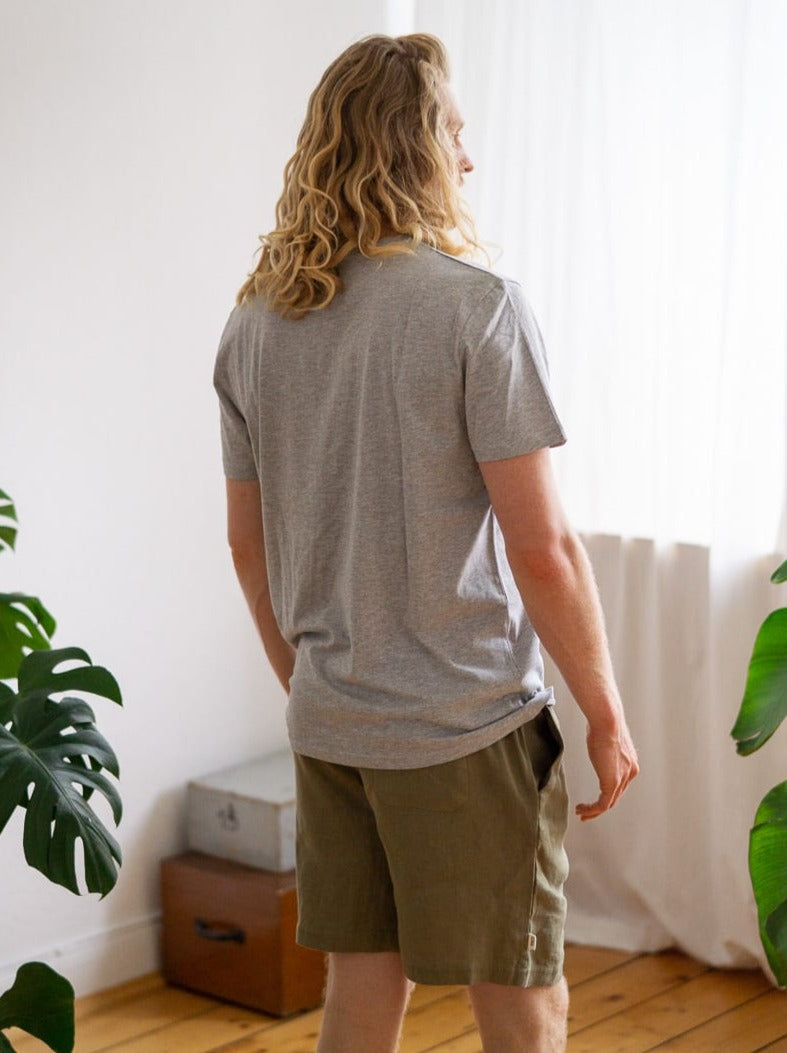 Rückansicht von unserem Freund Mo, der das Fair Fashion Schweres Basic T-Shirt in grau von FUXBAU aus 100% Biobaumwolle trägt