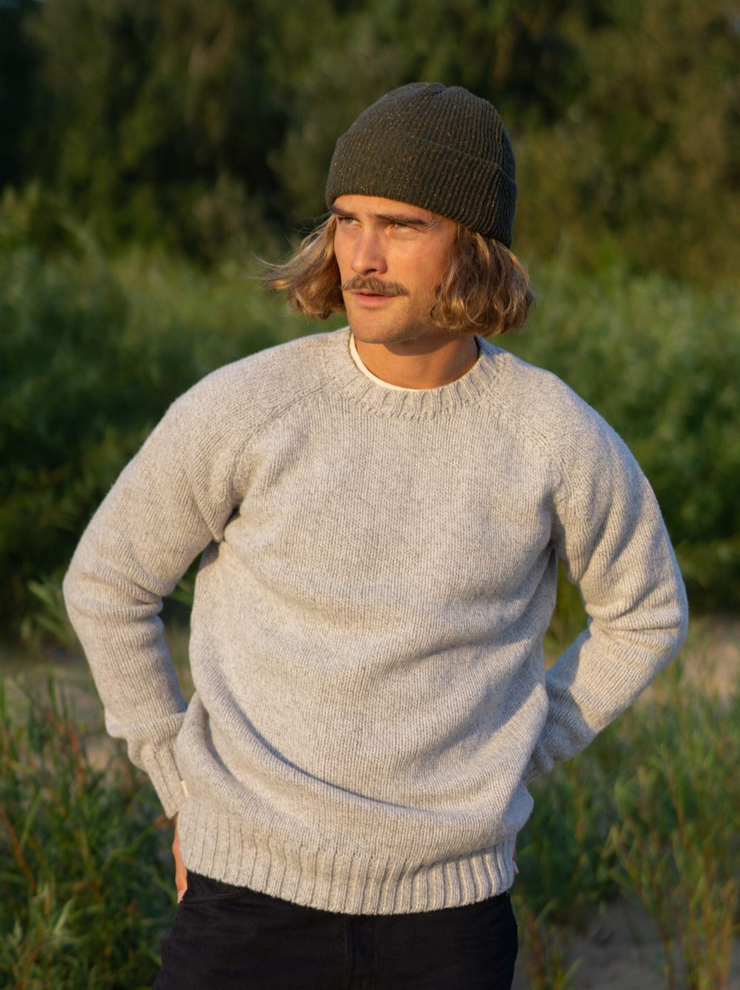Kelsey trägt unseren Nachhaltiger Männer Merino Strickpullover in grau aus 100% Merinowolle