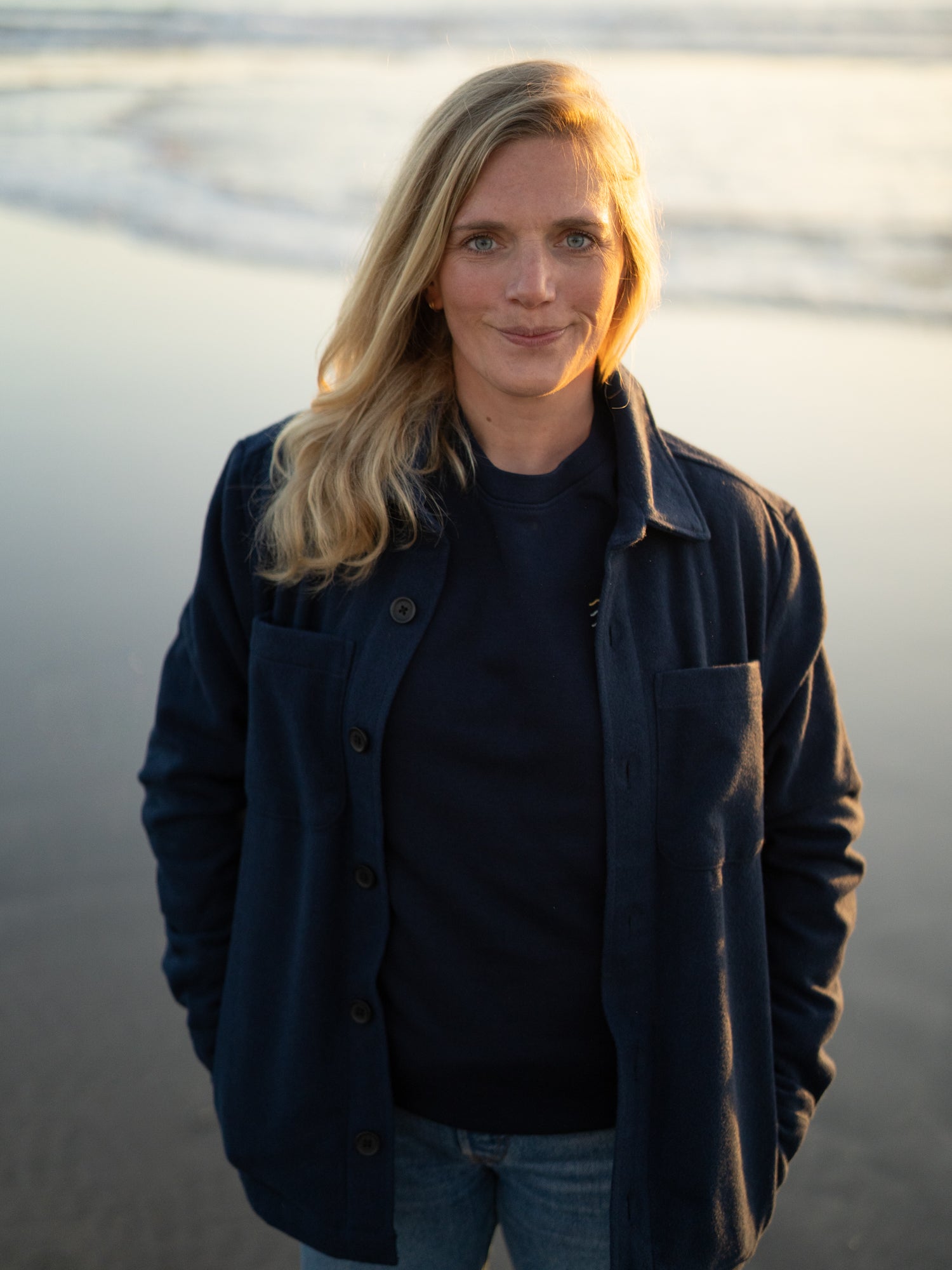 Isi trägt unsere faire und nachhaltige Hemdjacke in navy am Strand