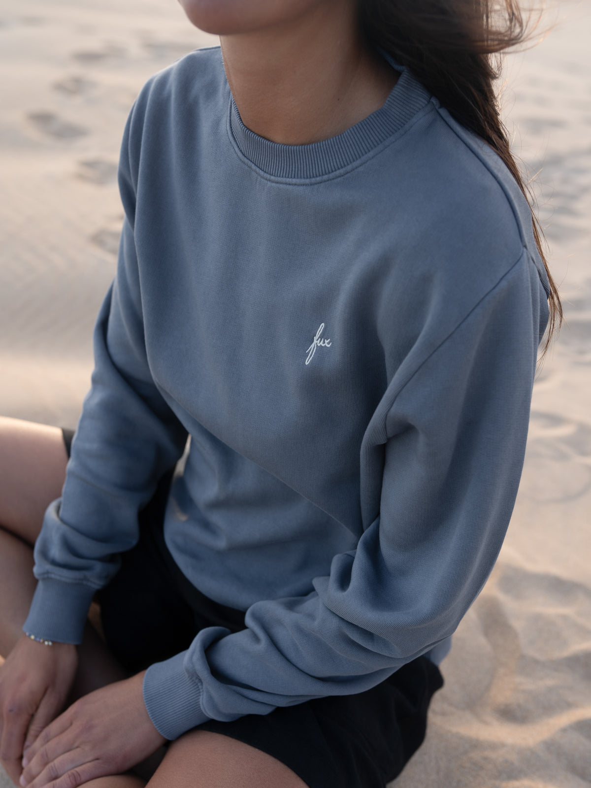 Detailaufnahme vom seeblauen FUXBAU Frauen Pullover aus Biobaumwolle am Strand