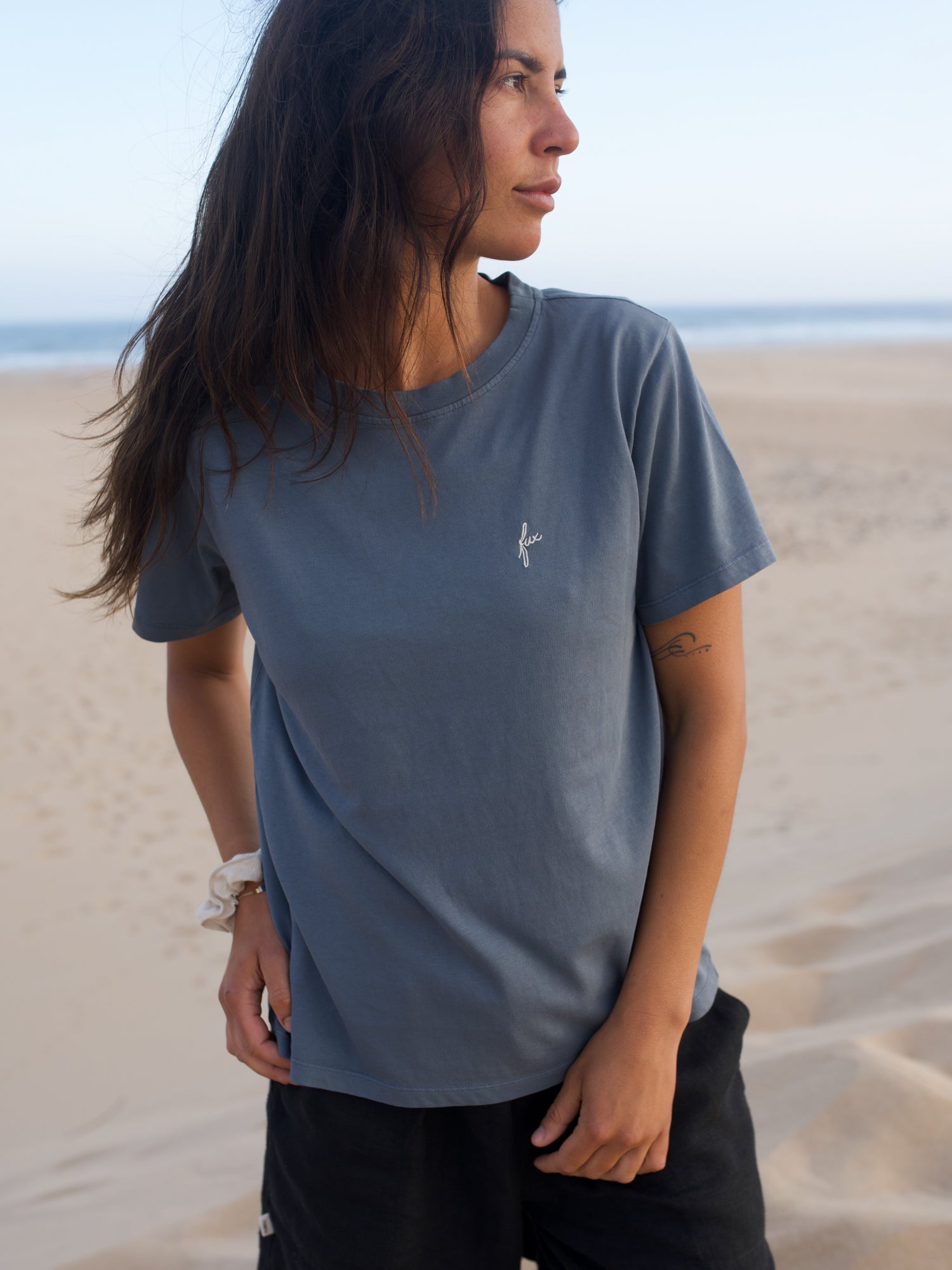 Frau trägt seeblaues FUXBAU T-Shirt aus Biobaumwolle am Strand in Portugal