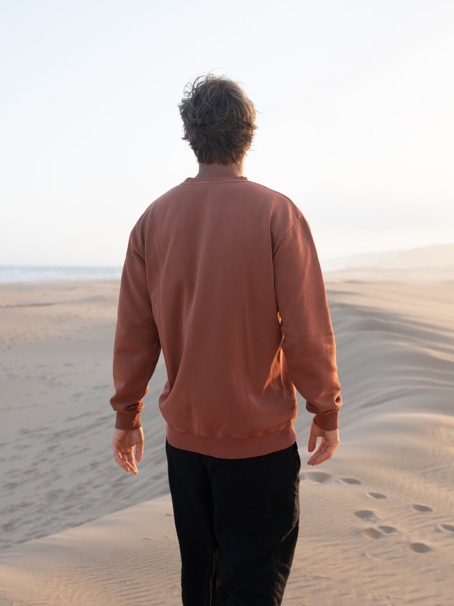 Rückansicht vom roten Männer Pullover von FUXBAU vor Strand und Meer in Portugal