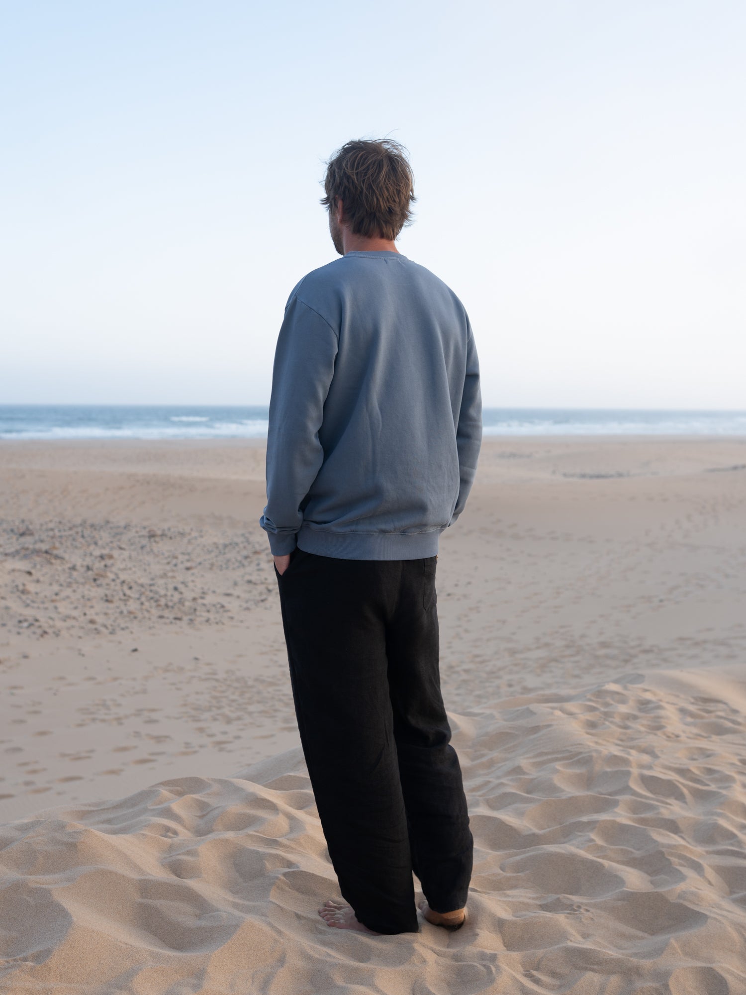 Rückansicht vom seeblauen Männer Pullover von FUXBAU am Strand in Portugal