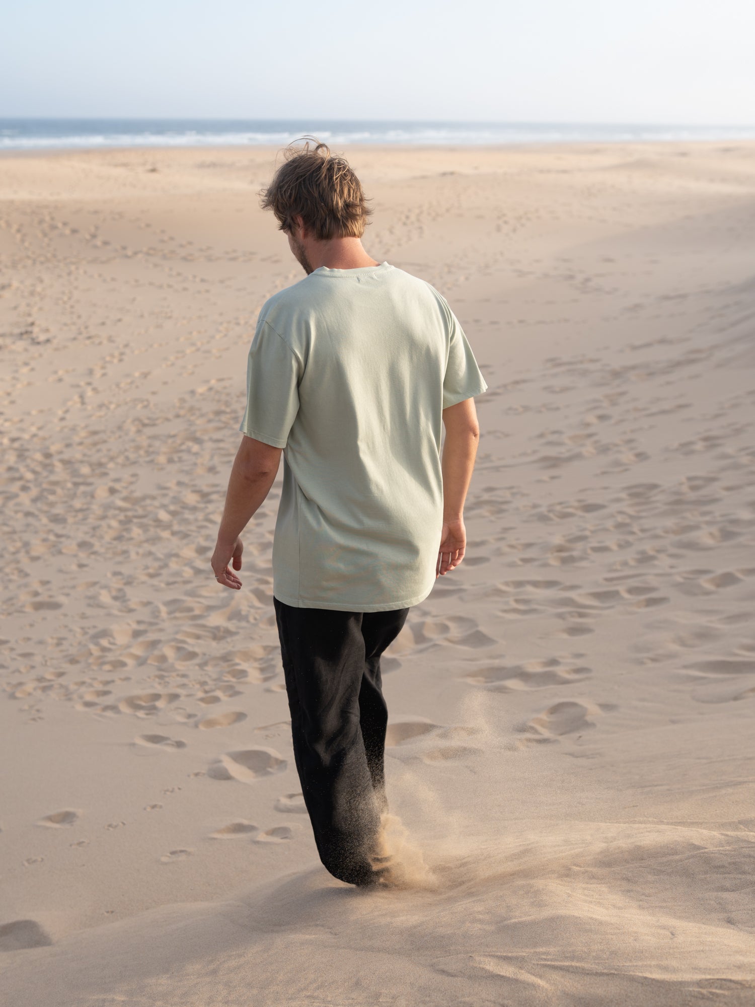 Rückansicht vom seegrünen FUXBAU Männer T-Shirt aus Biobaumwolle am Strand