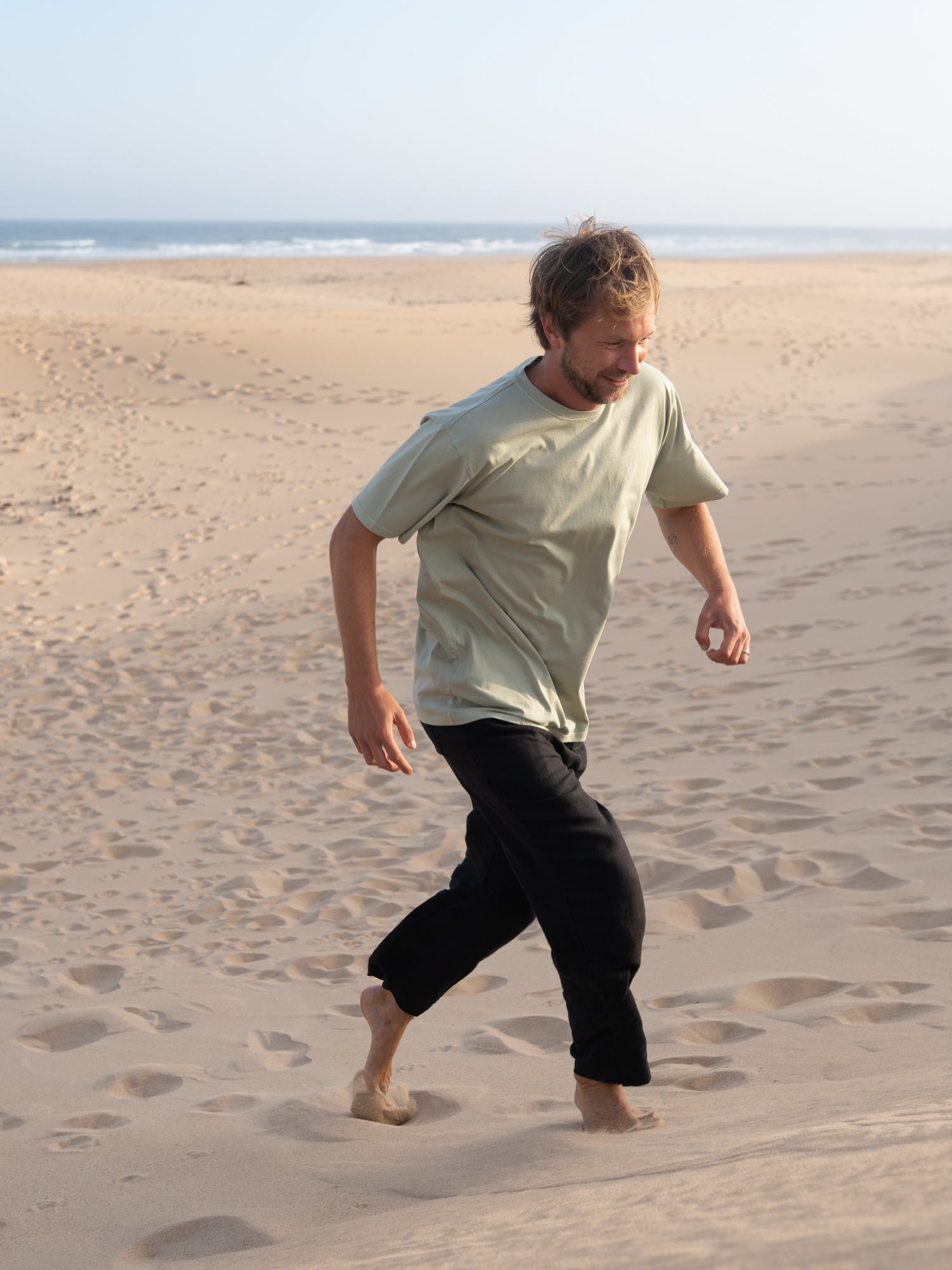 Mann trägt stückgefärbtes seegrünes FUXBAU T-Shirt aus Biobaumwolle in Portugal
