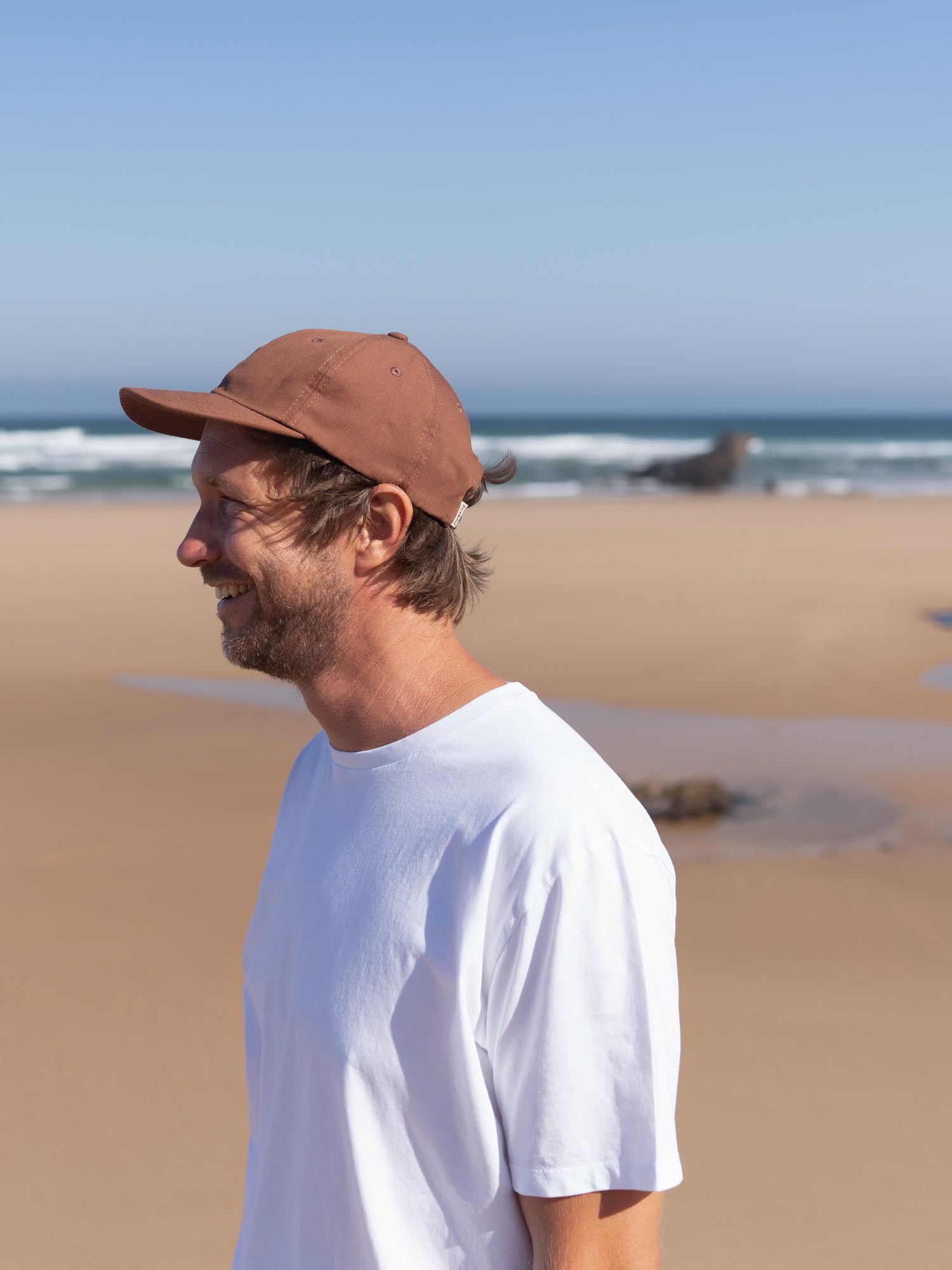 Seitenansicht der kastanie Unisex Dad Cap am Strand