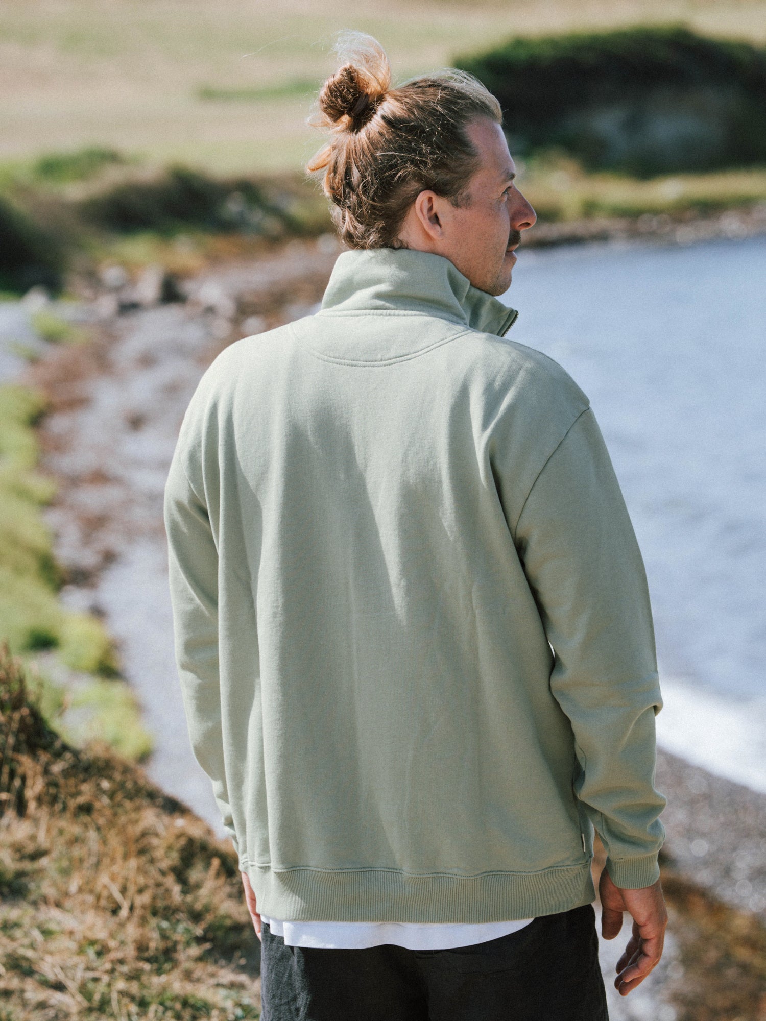 Männer Half Zip Sweater in Seegras aus Biobaumwolle von hinten am Meer