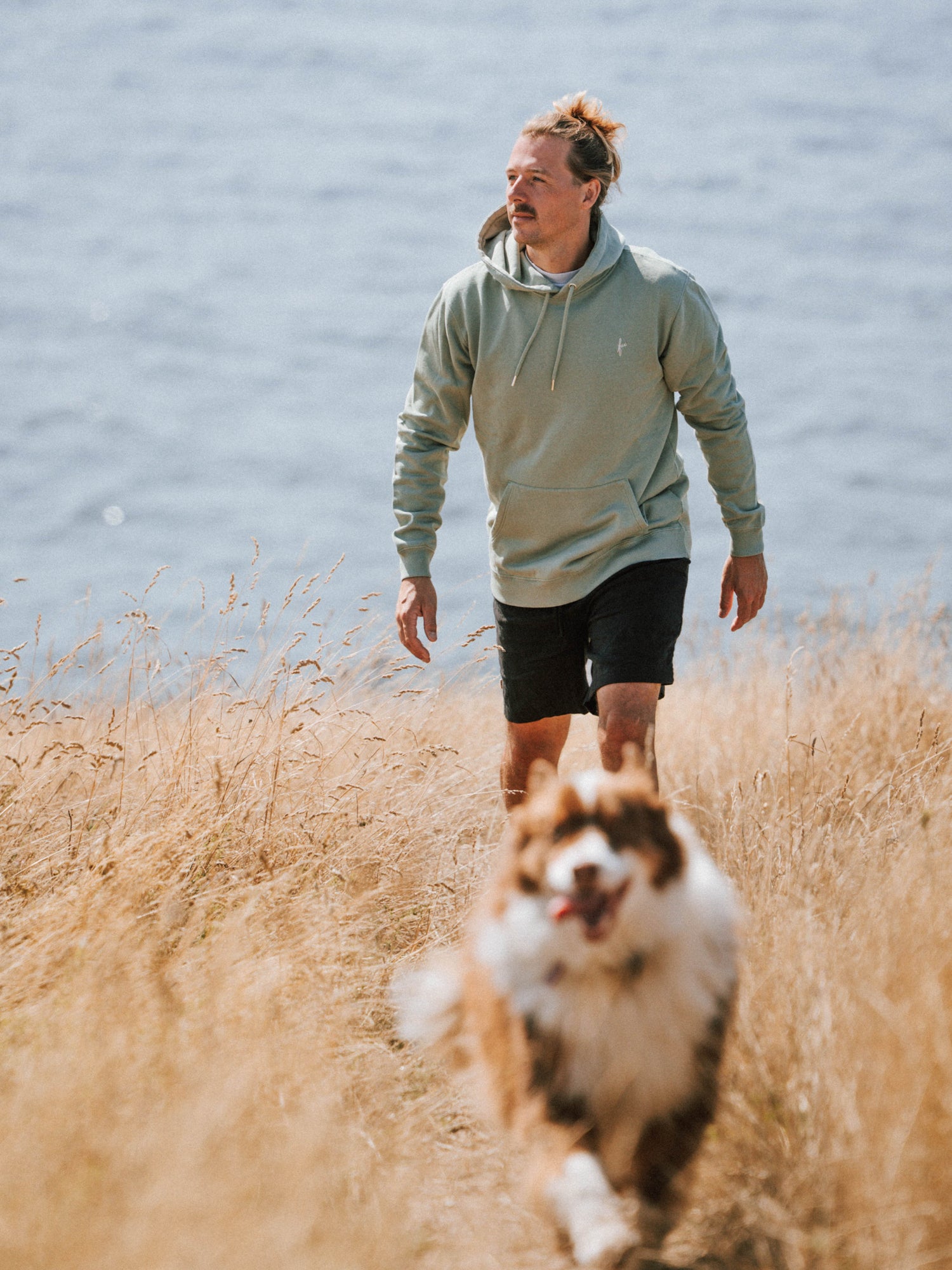 Unisex Hoodie in Seegras aus Biobaumwolle beim Spaziergang an der Küste