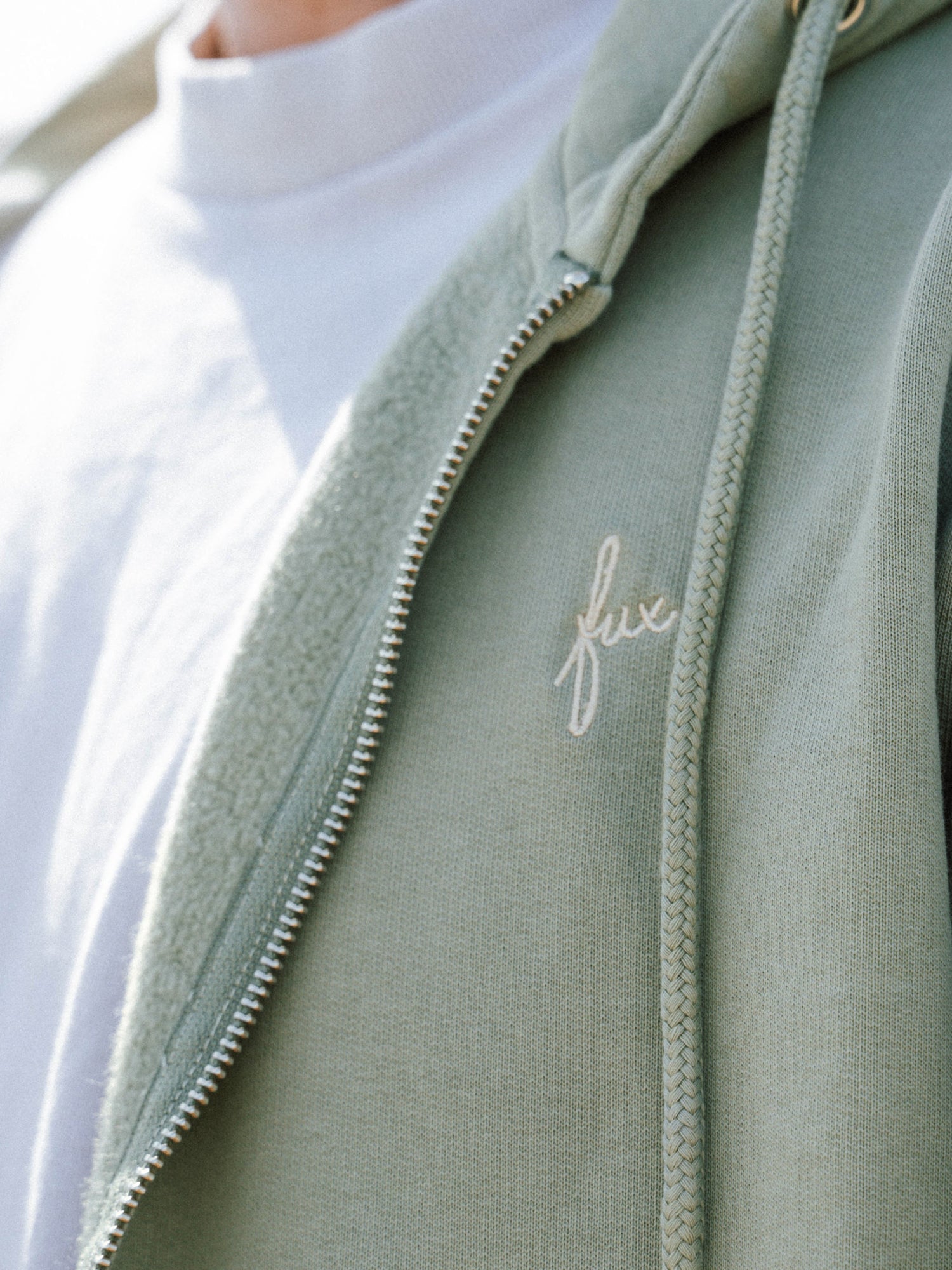 Detailaufnahme der Unisex Sweatjacke in Seegras aus Biobaumwolle mit fux Stick und Reißverschluss