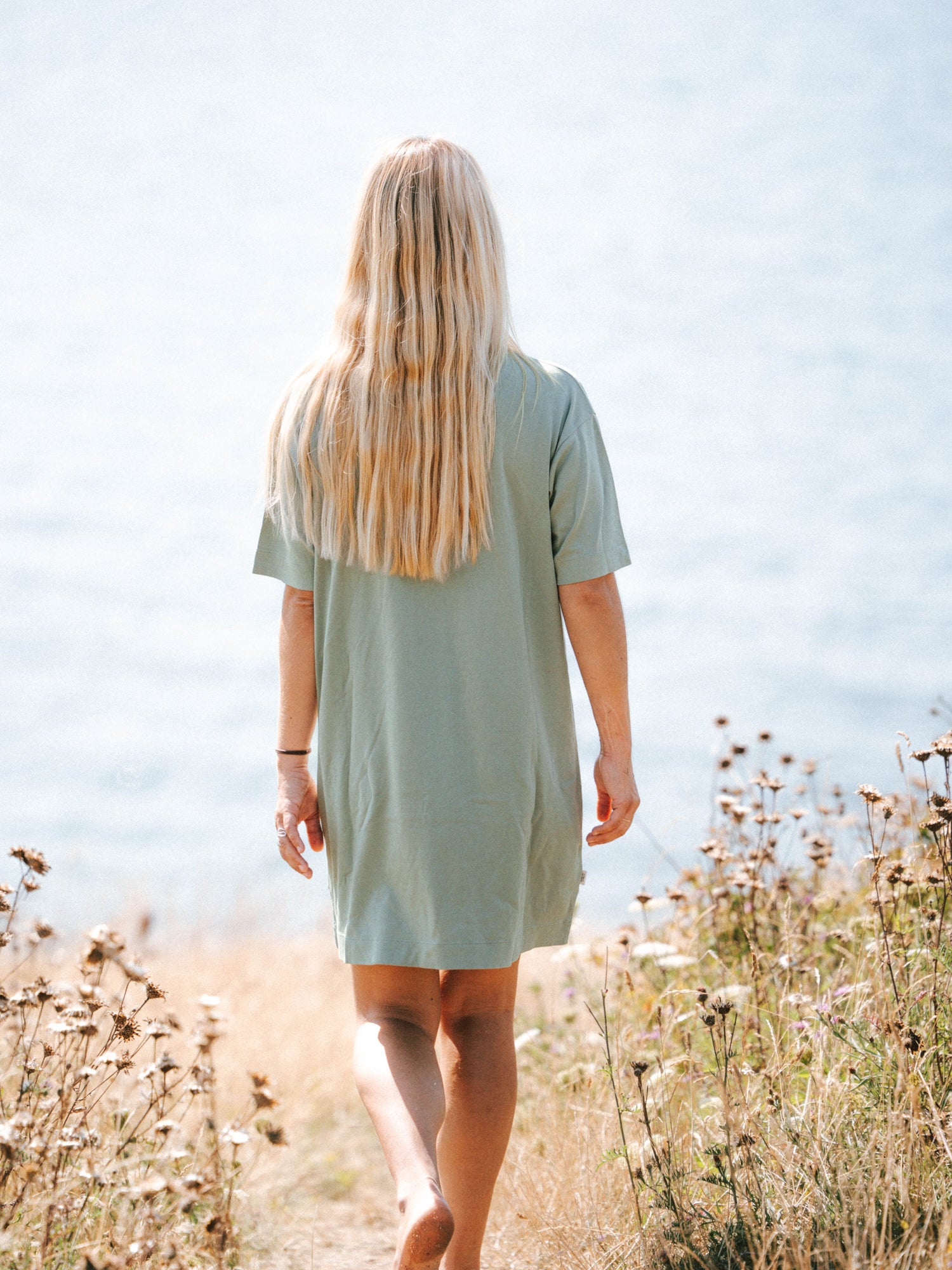 Frauen T-Shirt Kleid in Seegras aus Biobaumwolle von hinten am Meer