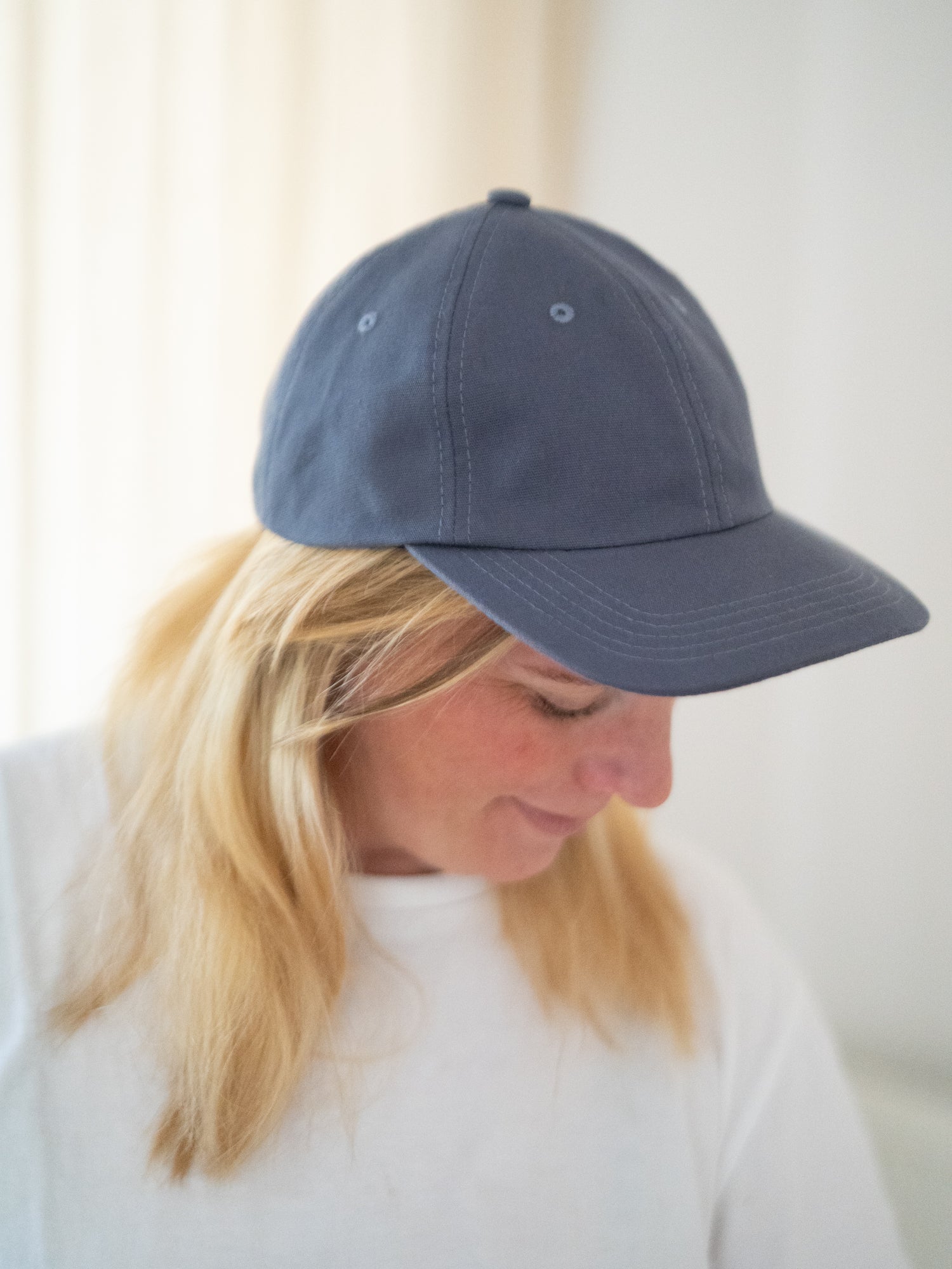 Unisex Dad Cap in blaugrau aus 100% Biobaumwolle und fair in Europa hergestellt, getragen von einer blonden Frau