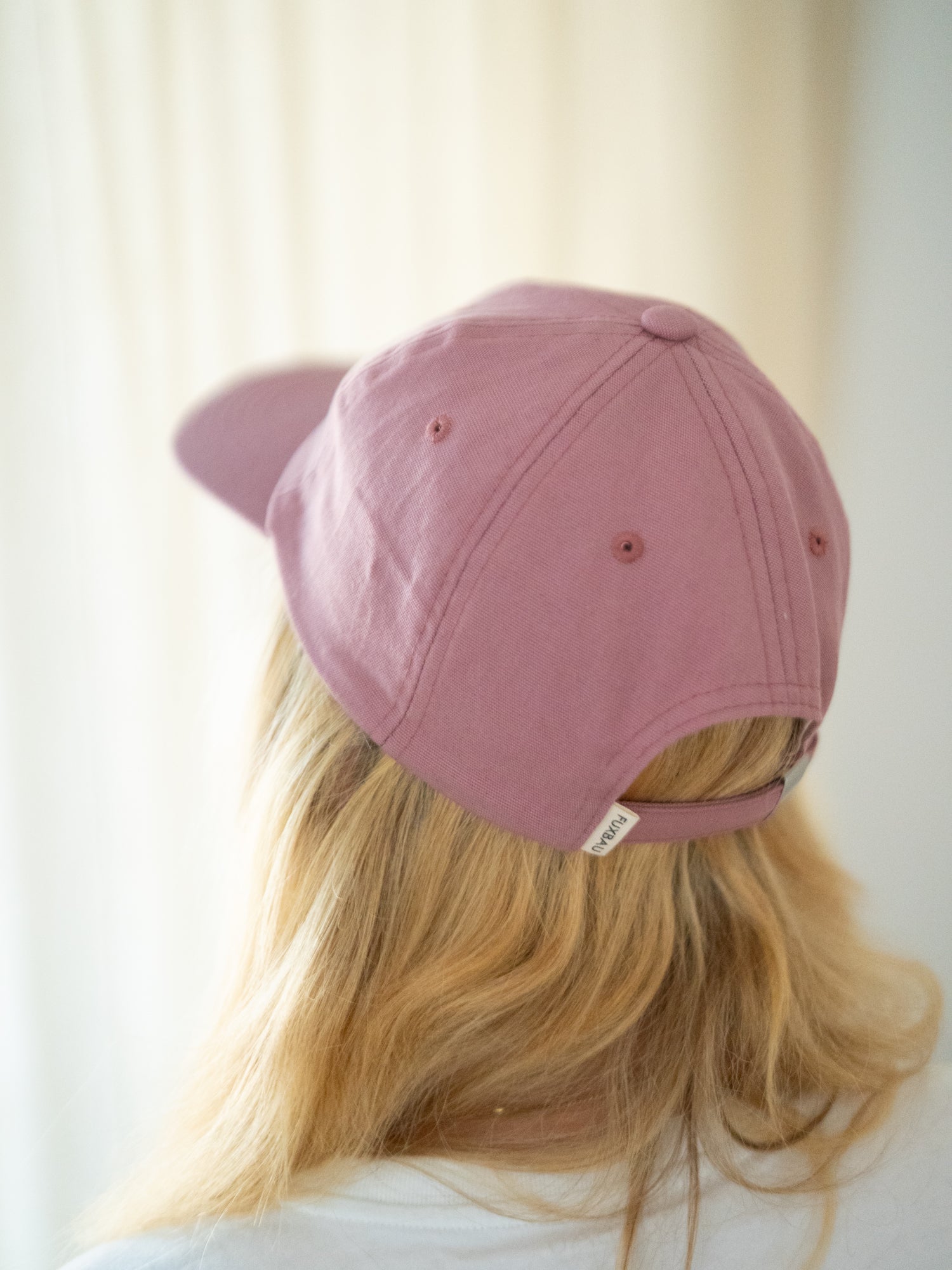Unisex Dad Cap in hellrot getragen von einer blonden Frau