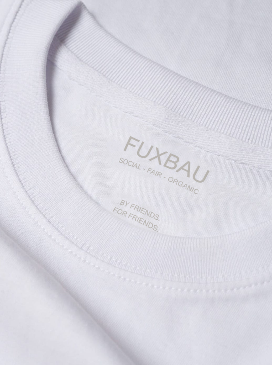 Detailbild eines nachhaltiges FUXBAU Männer Basic T-Shirt in weiß mit einem Ton in Ton  Imprint. Gefertigt aus 100% Biobaumwolle.