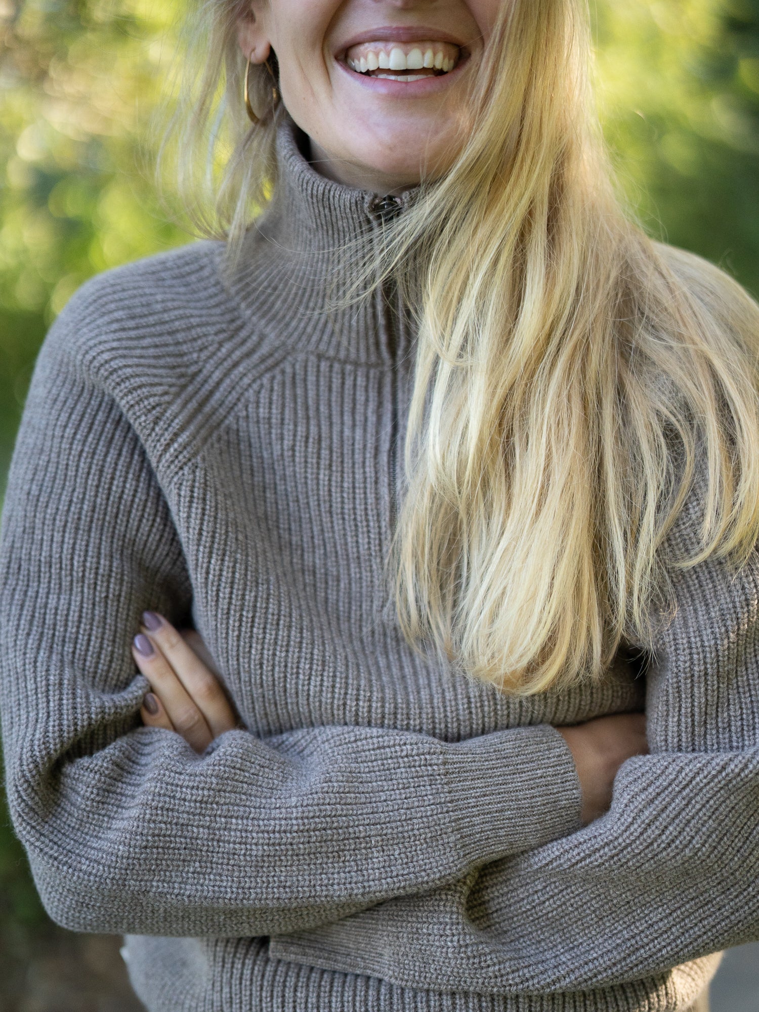 Nachhaltiger Fair Fashion Frauen Merino Troyer in braun meliert aus 100% Merino Schurwolle Made in Italy, getragen von einer jungen Frau, die in die Kamera lacht.