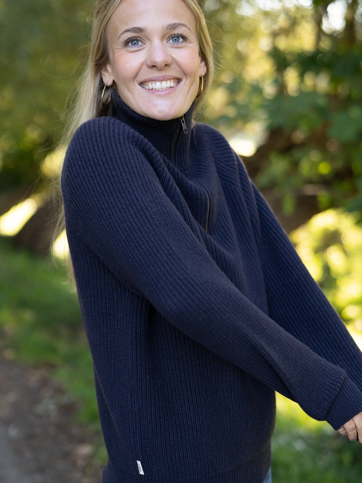 Nachhaltiger Fair Fashion Frauen Merino Troyer in navy aus 100% Merino Schurwolle in navy Made in Italy, getragen von einer jungen Frau mit seitlicher Ansicht.