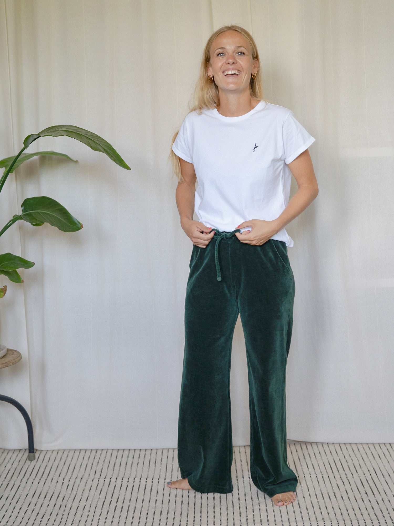 Frau trägt die dunkelgrüne FUXBAU Samthose Greta aus GOTS-zertifizierter Biobaumwolle – nachhaltige Fair Fashion Hose mit weitem Bein.