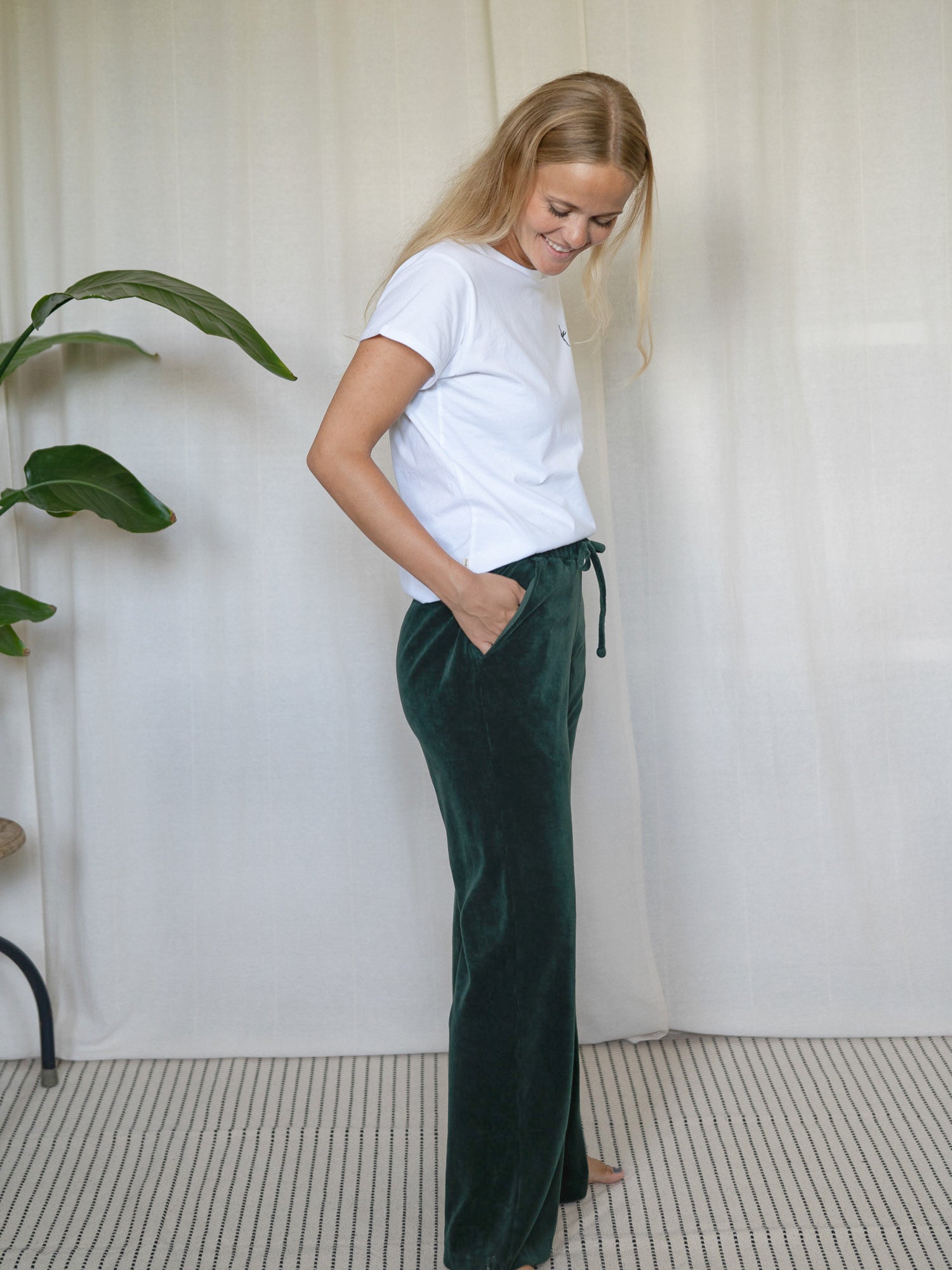 Frau in seitlicher Pose mit dunkelgrüner FUXBAU Samthose Greta – nachhaltige Loungehose aus GOTS-zertifizierter Biobaumwolle.
