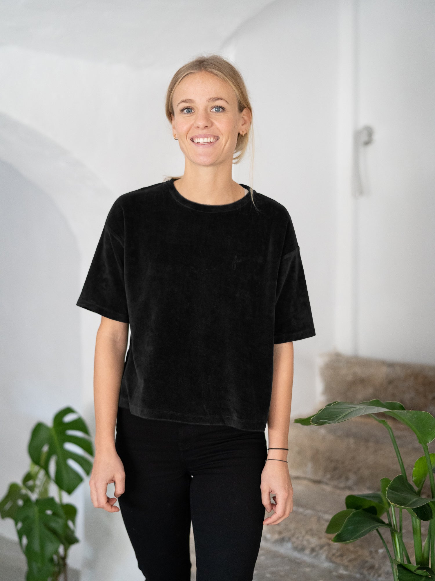 Greta trägt das nachhaltige Frauen Cropped Samt T-Shirt in schwarz aus 100% Biobaumwolle