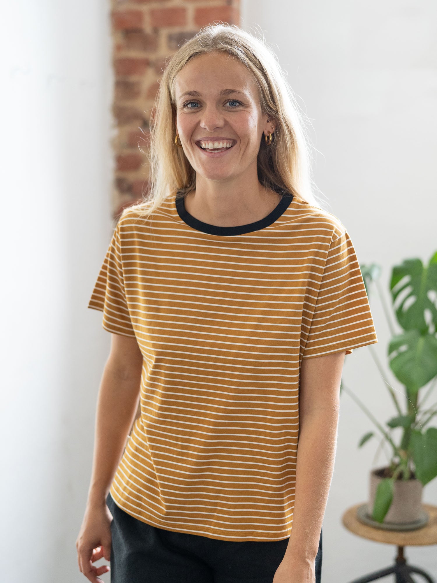 100% Biobaumwolle & Made in Portugal: Greta trägt das Greta trägt das nachhaltige gestreiftes Frauen T-Shirt in senfgelb von FUXBAU