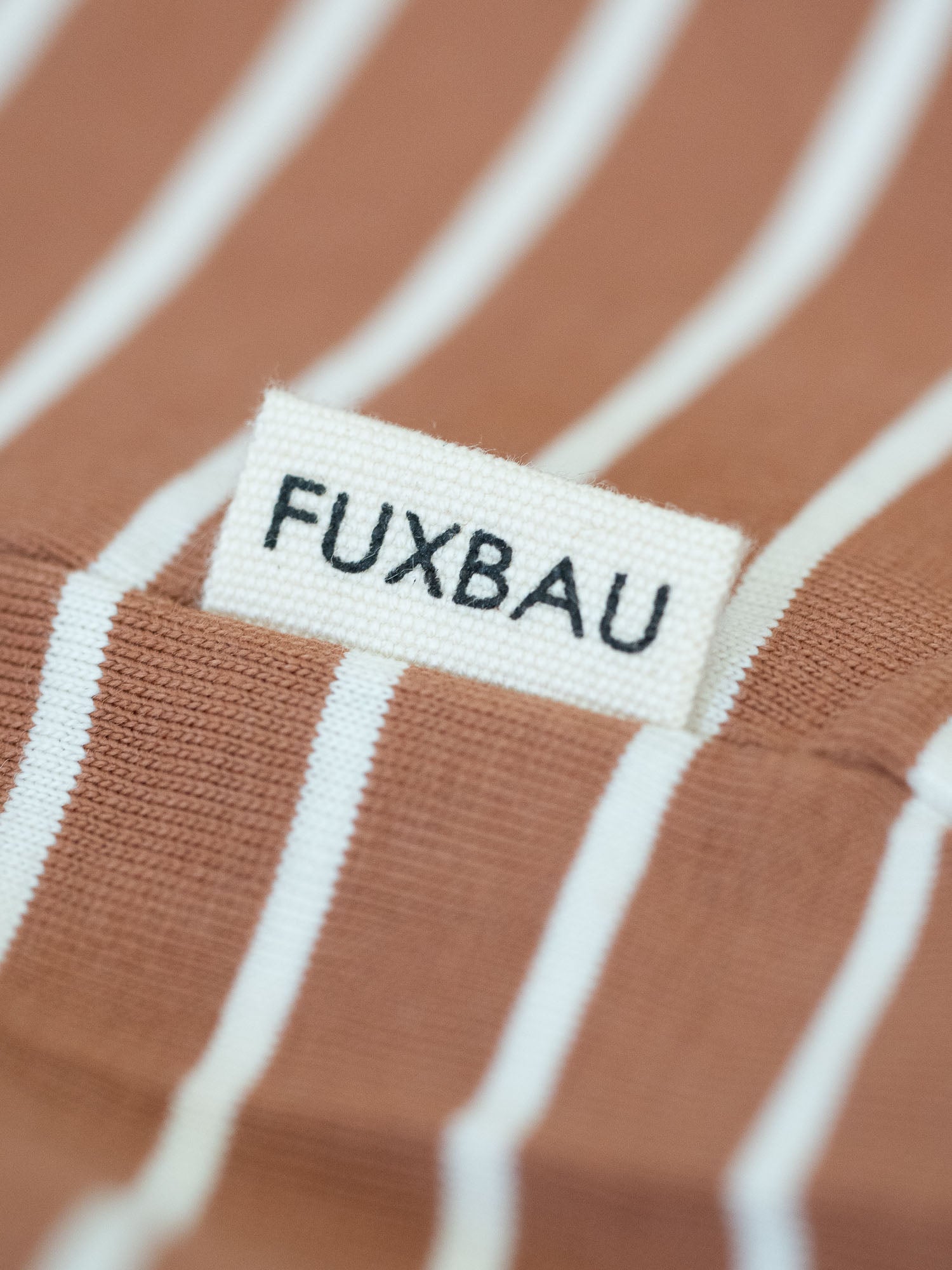 Detailansicht von einer Sideflags eines gestreiften FUXBAU Fair Fashion T-Shirt aus Biobaumwolle in schwarz, weiss und karamell. 