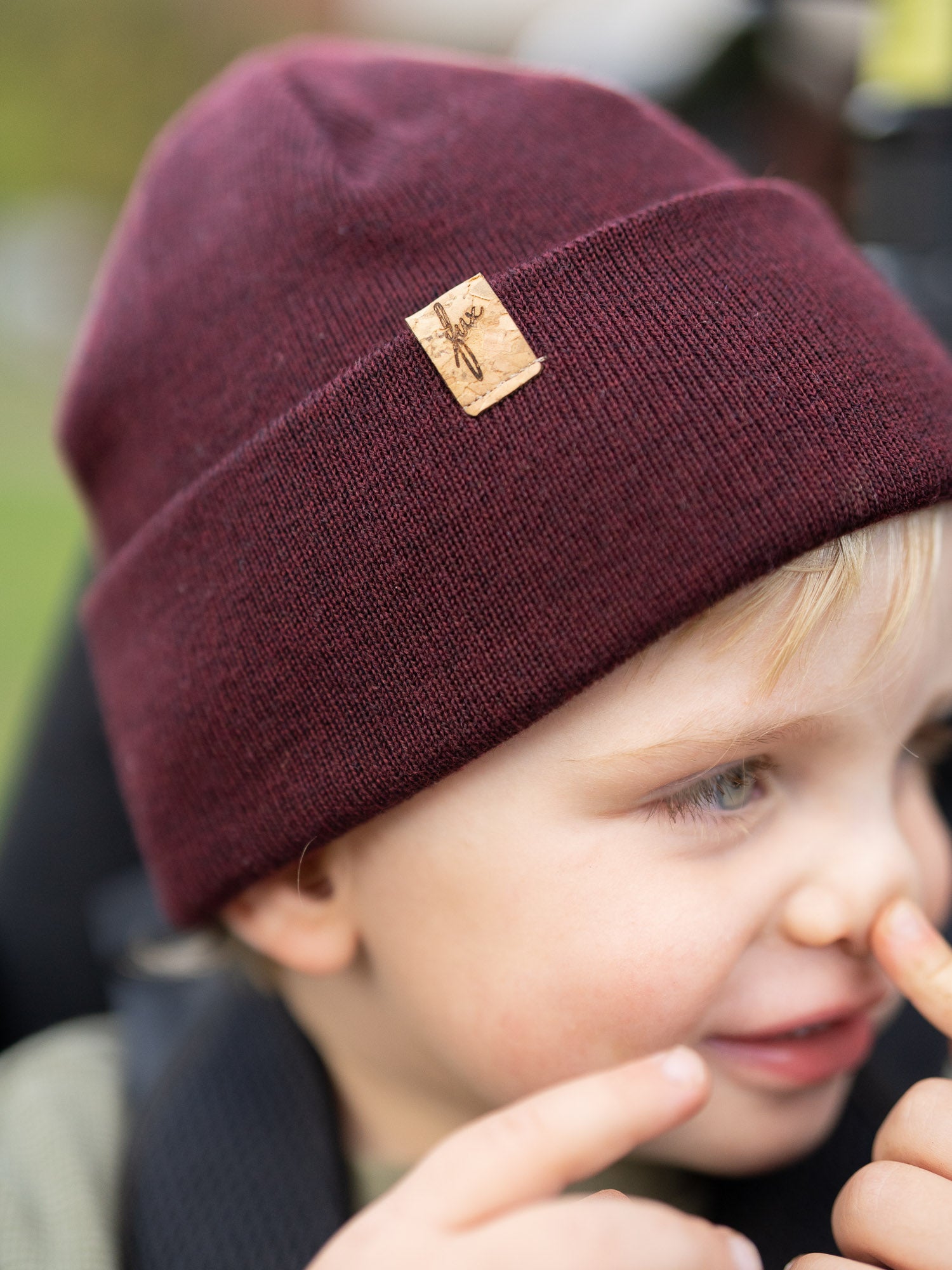 Kind mit bordeauxfarbener FUXBAU Kinder Merino Kork Beanie – nachhaltige Mütze aus 100% Merinowolle, fair produziert in Deutschland mit Kork-Logo-Patch.