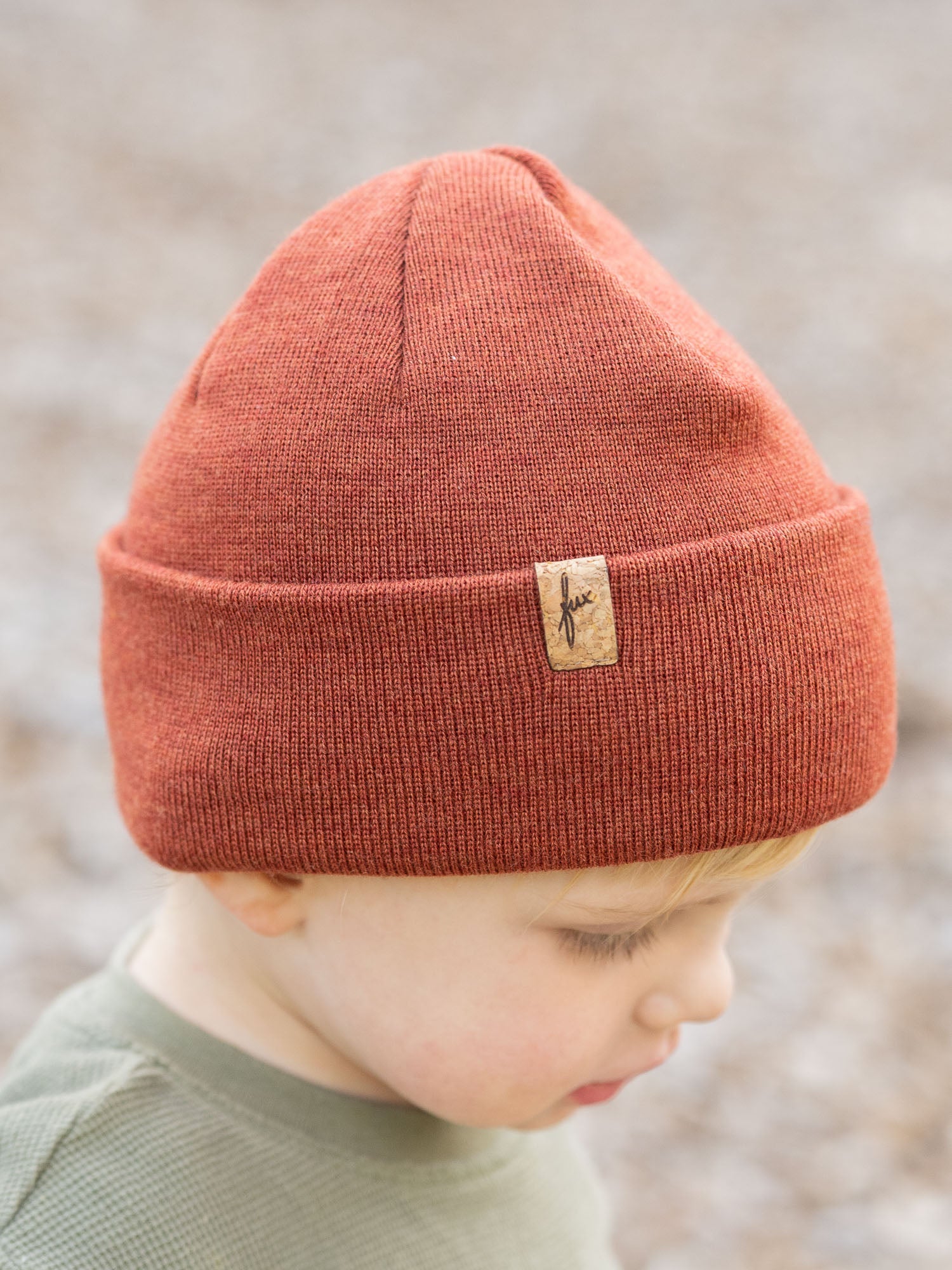 Kind seitlich mit herbstorangener Kinder Merino Kork Beanie von FUXBAU – Fair Fashion aus weicher Merinowolle, hergestellt in Deutschland mit Kork-Patch.
