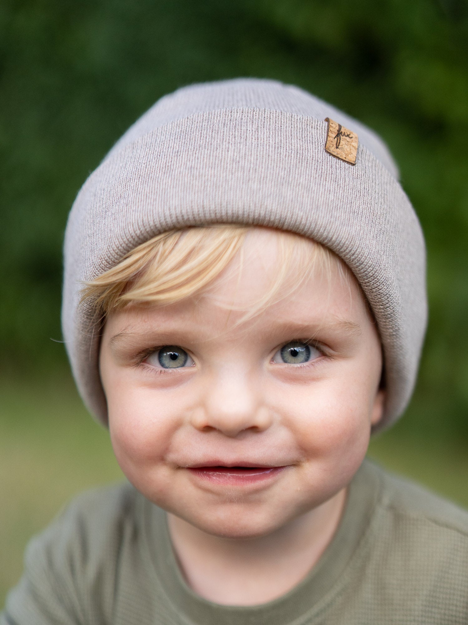Frontalaufnahme eines Kindes mit sandfarbener FUXBAU Kinder Merino Kork Beanie – nachhaltige Mütze aus 100% Merinowolle, fair produziert in Deutschland.