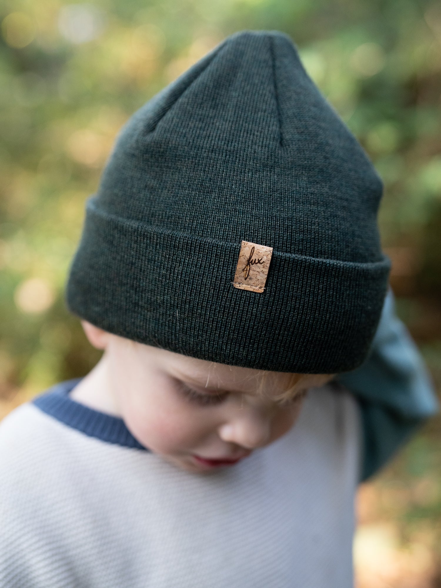 Kind trägt nachhaltige FUXBAU Kinder Merino Beanie in Waldgrün mit Kork-Label – fair produziert in Deutschland.