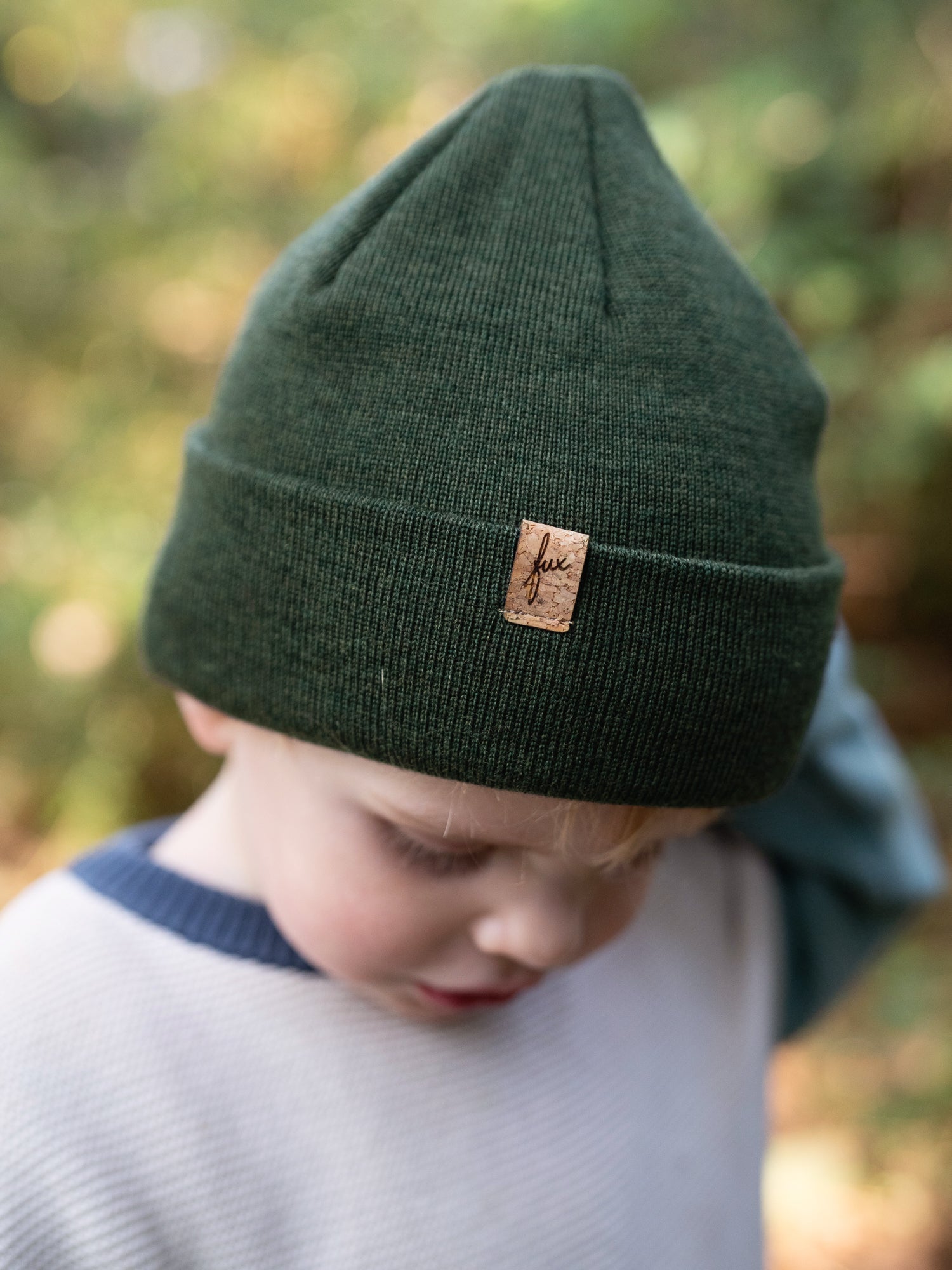 Kind trägt nachhaltige FUXBAU Kinder Merino Beanie in Waldgrün mit Kork-Label – fair produziert in Deutschland.