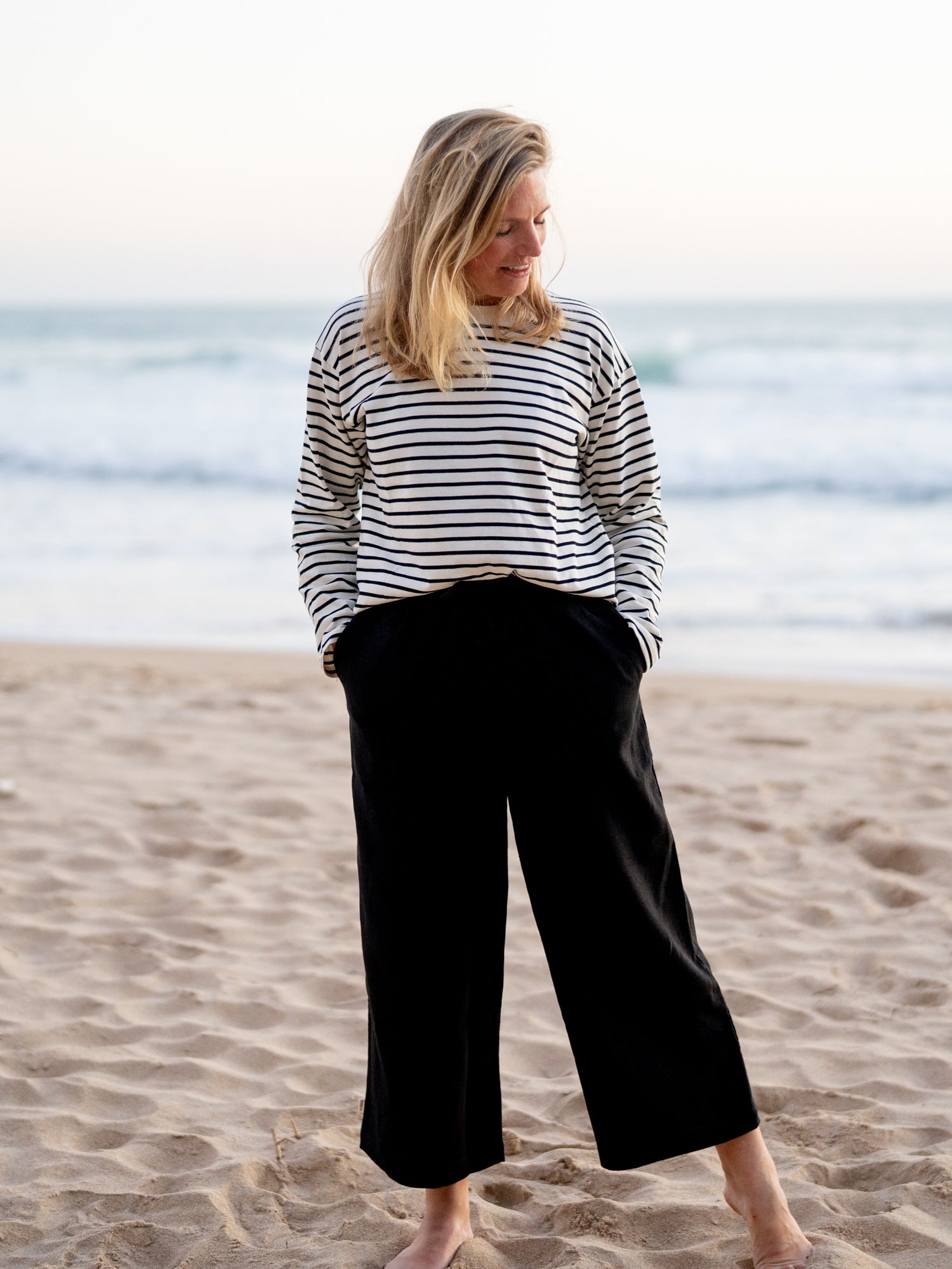 Nachhaltige FUXBAU Fair Fashion Frauen Leinehose in schwarz aus 100% Leinen getragen am Strand in Spanien.
