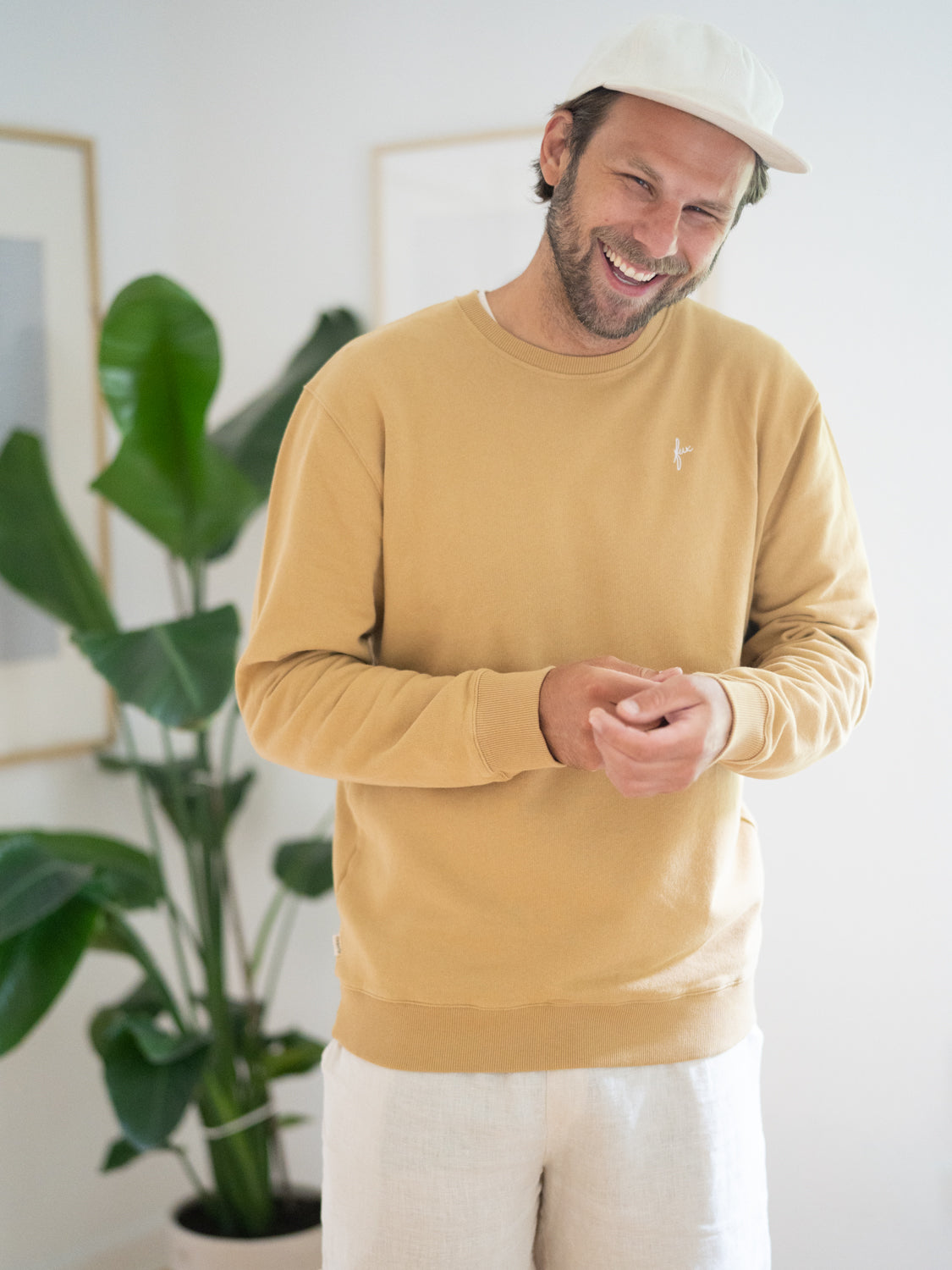 Philipp trägt den Friendly Fabrics Männer Sweater in senfgelb, der aus Reststoffen gefertigt wird.