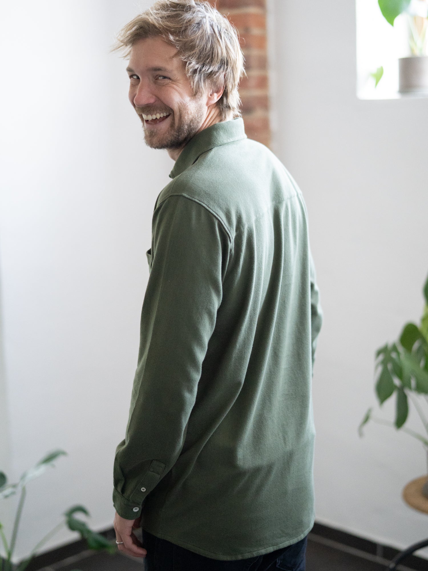 Ein junger, blonder Mann trägt ein nachhaltiges und fair gefertigtes Männer Hemd aus 100% GOTS zertifizierte Biobaumwolle in grün von FUXBAU.