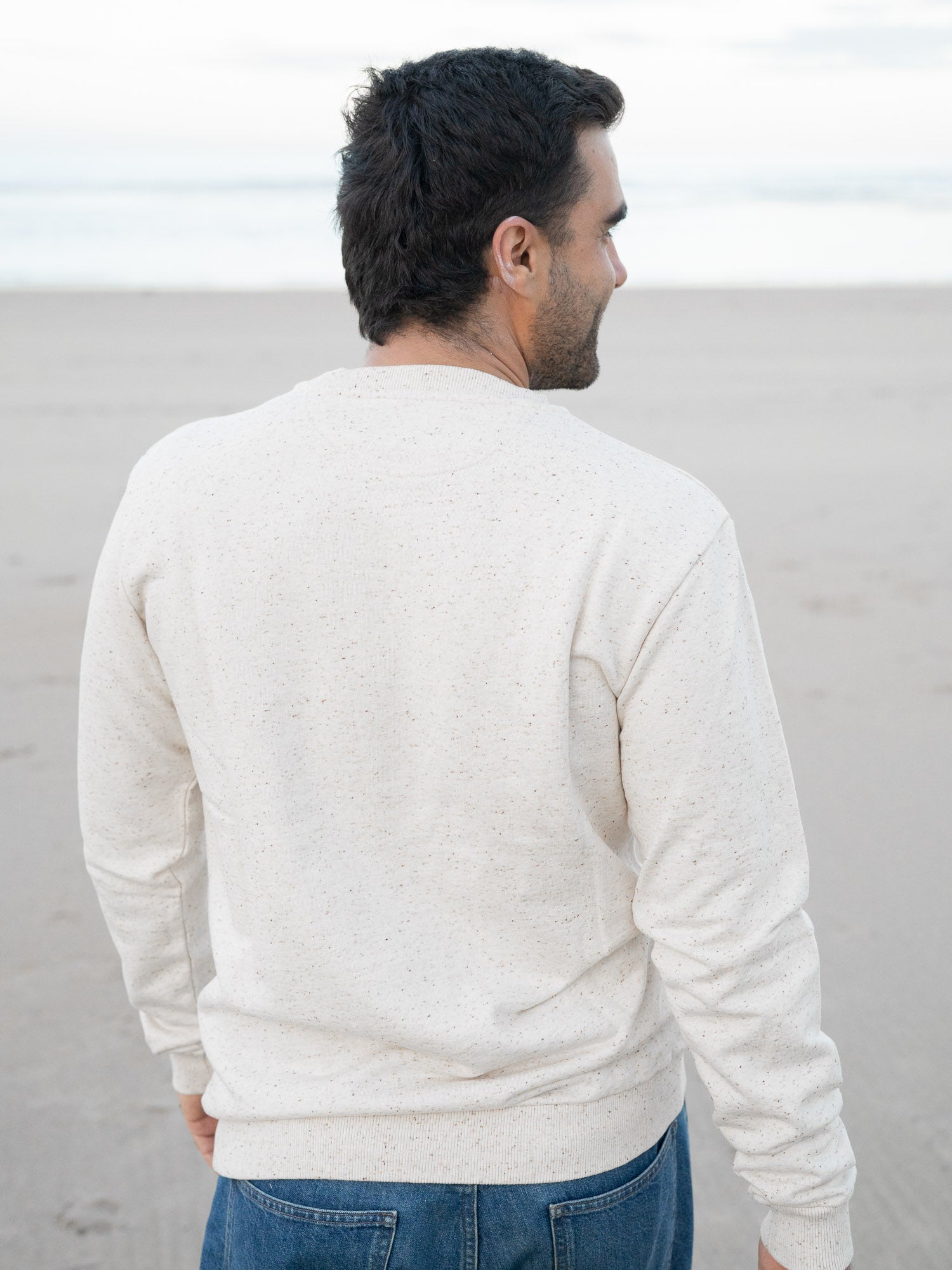 Guillermo trägt unseren FUXBAU Pullover mit Highlights aus GOTS zertifizierter Biobaumwolle in beige Made in Portugal.