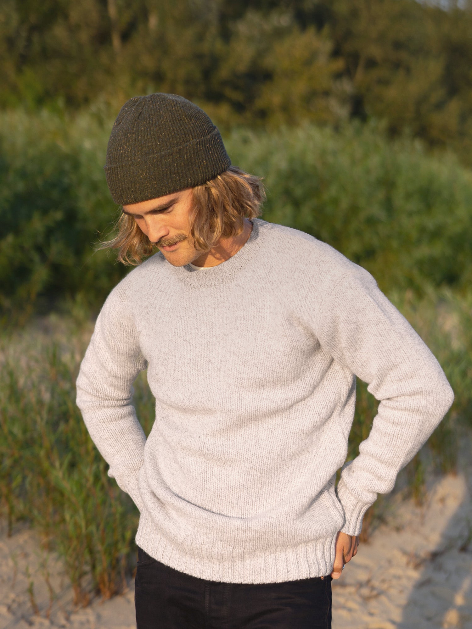 Kelsey trägt unseren nachhaltigen Männer Merino Strickpullover in beige aus 100% Merinowolle und fair in Deutschland hergestellt