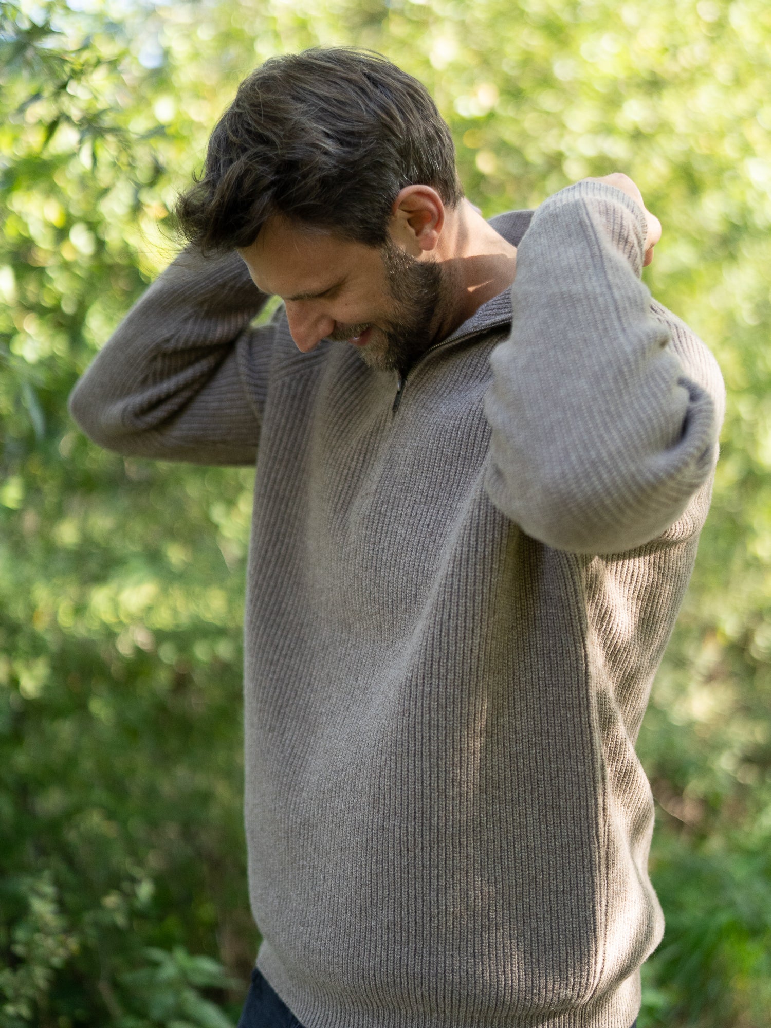 Nachhaltiger Fair Fashion Männer Merino Troyer in braun meliert aus 100% Merino Schurwolle Made in Italy, getragen von einem jungen Mann der die Hand am Kragen hat.