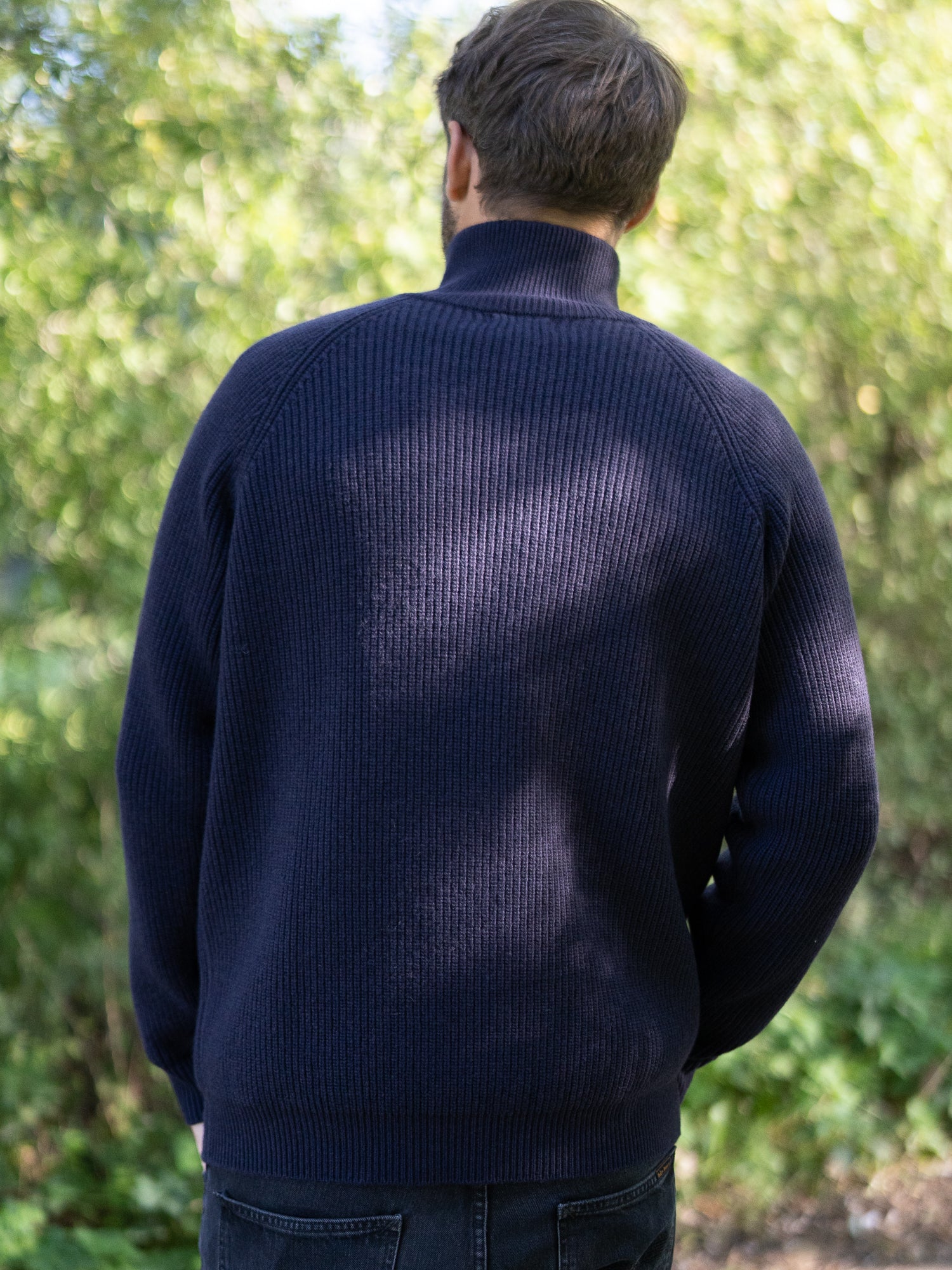 Nachhaltiger Fair Fashion Männer Merino Troyer in navy aus 100% Merino Schurwolle in navy Made in Italy, getragen von einem jungen Mann der mit dem Rücken zur Kamera steht.